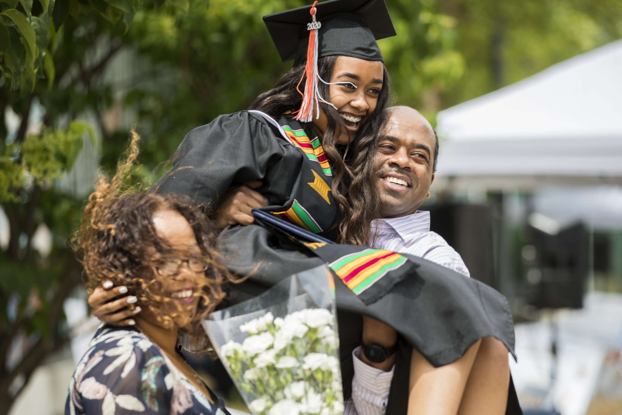  Hamartii Hailu is lifted by her father while receiving her diploma during a social distancing drive-up graduation ceremony at Cristo Rey Jesuit High School in Minneapolis on Saturday afternoon, June 6, 2020. (Liam James Doyle for MPR News) 