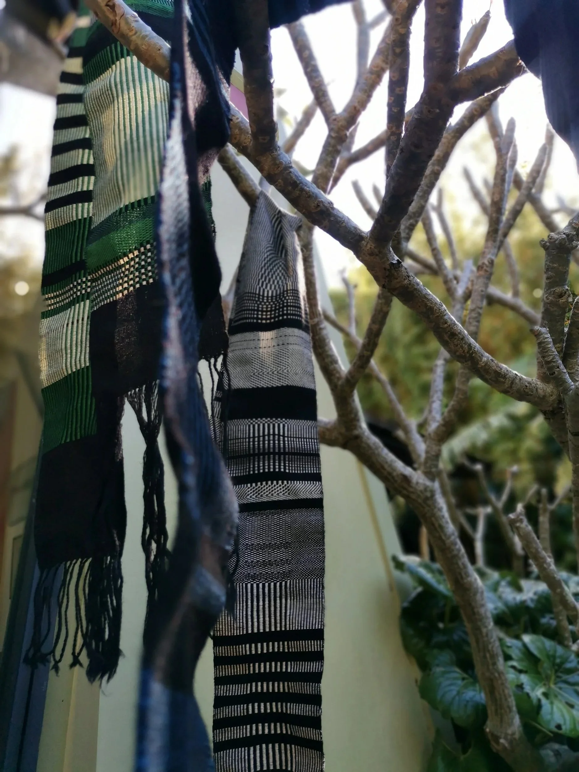 woven scarves hanging in a tree for display