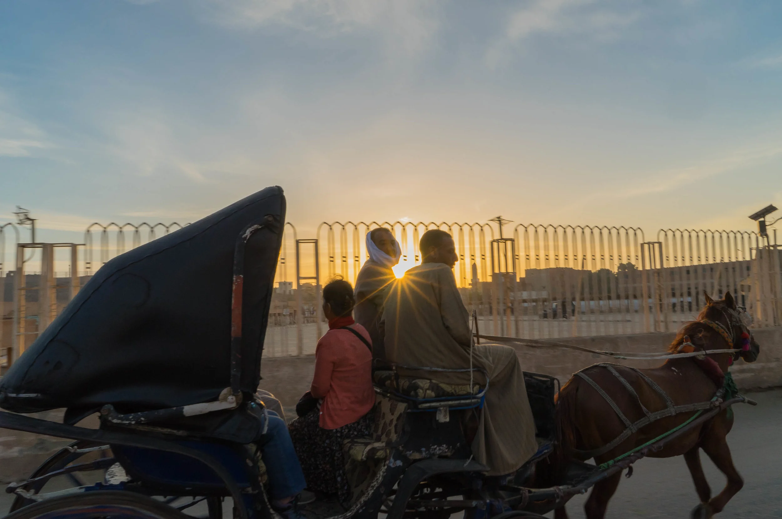 Two Egyptian men give a family of tourists a sunrise horse carriage ride in southern Egypt. 2017.