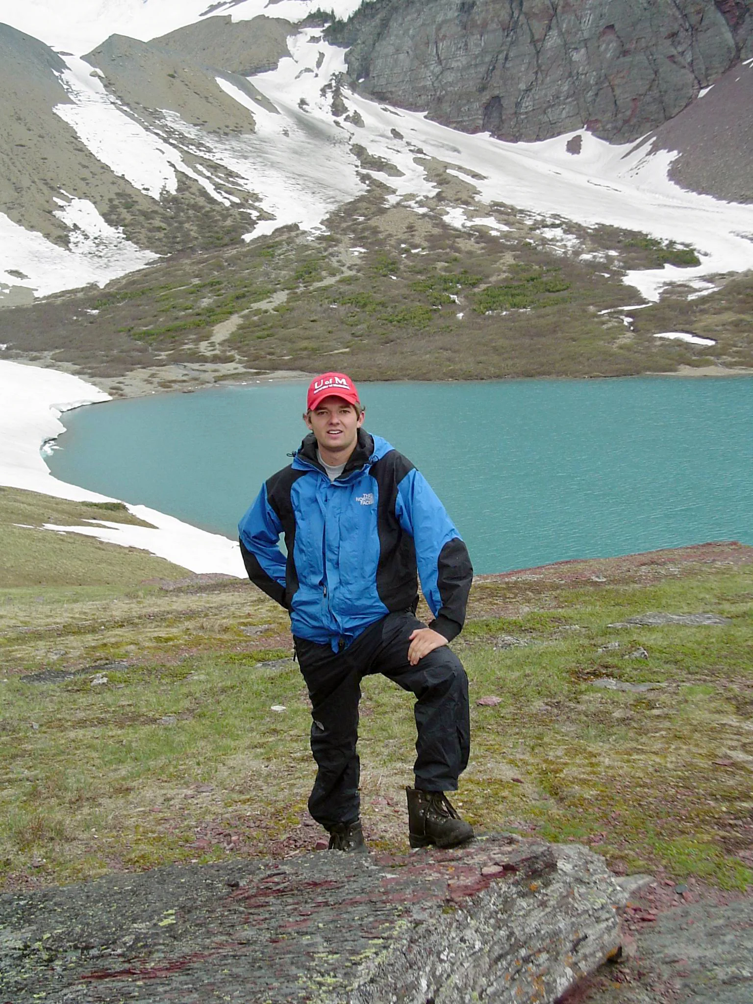 A stalwart hiker poses at Cracker Lake, very near the location of the Cracker Jack Mine. Photo Credit to Howard Stone.