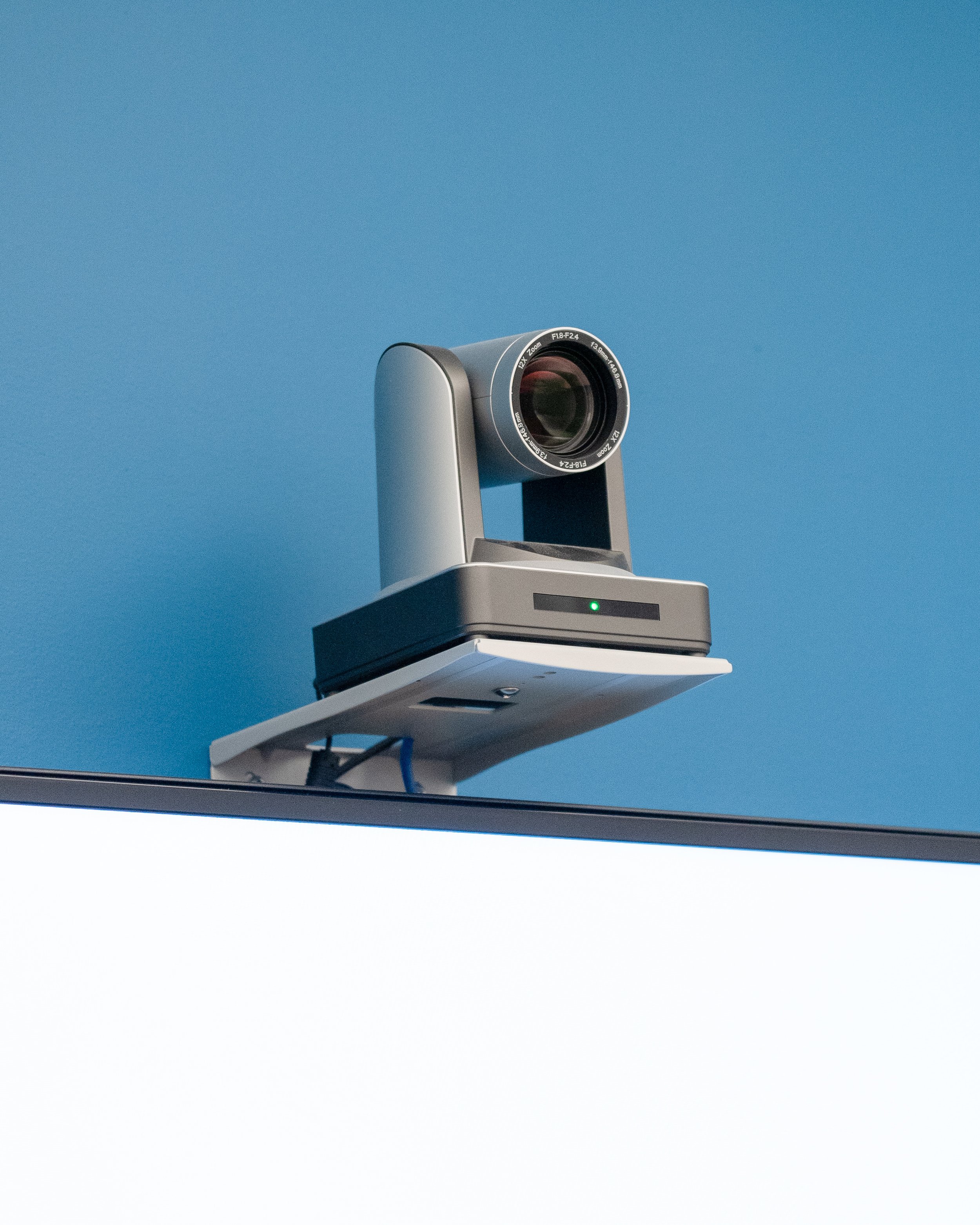  A boardroom camera mounted above an interactive touchscreen display/TV. 