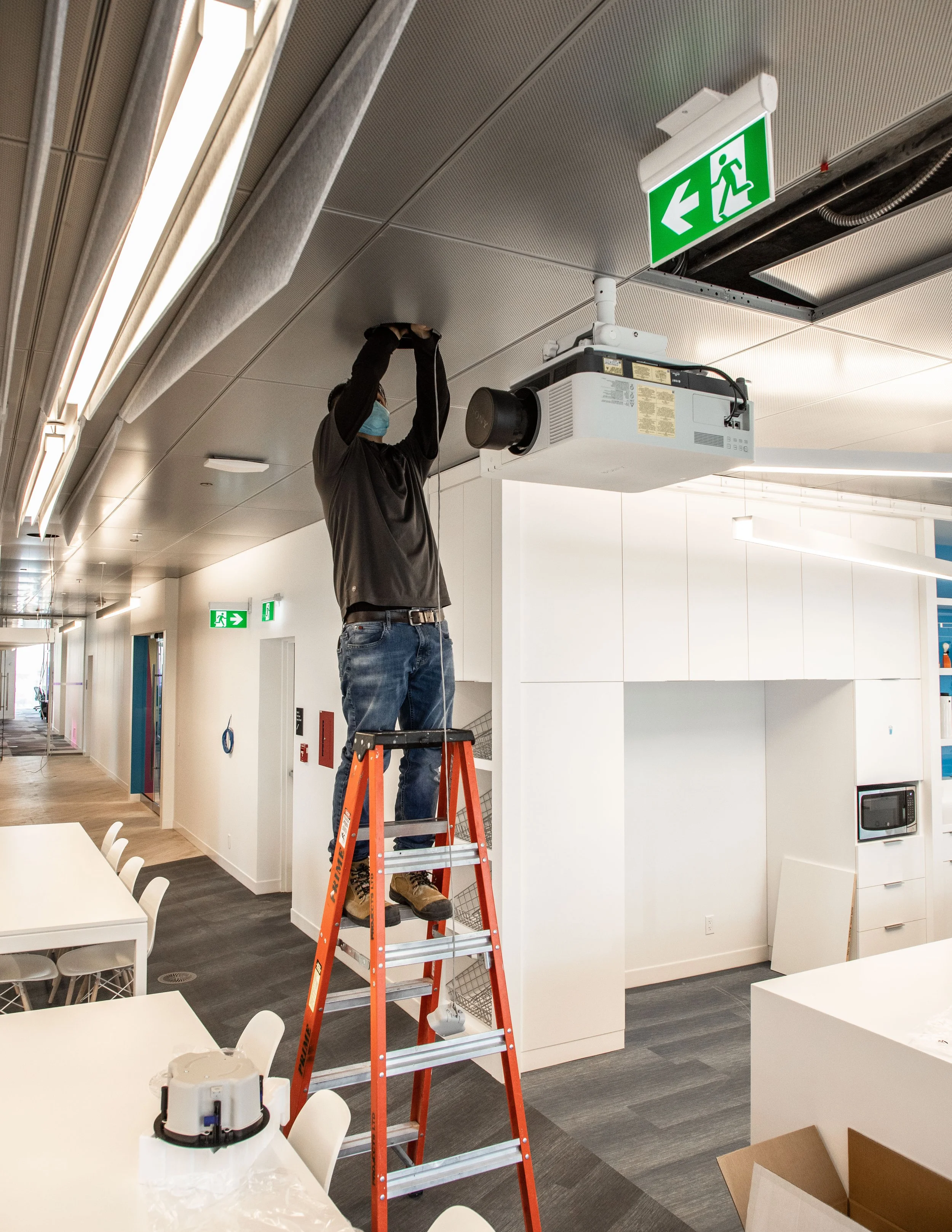 An AV technician working to install an audio system in a corporate office