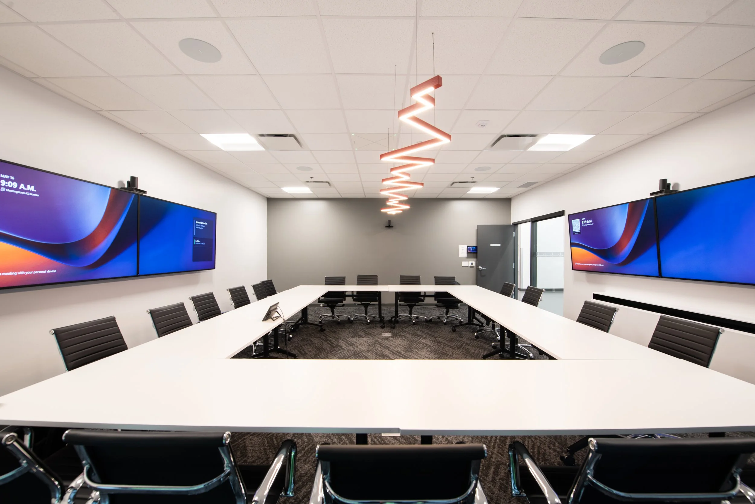 Boardroom with multiple displays, cameras, microphones, speakers, and unique lighting.