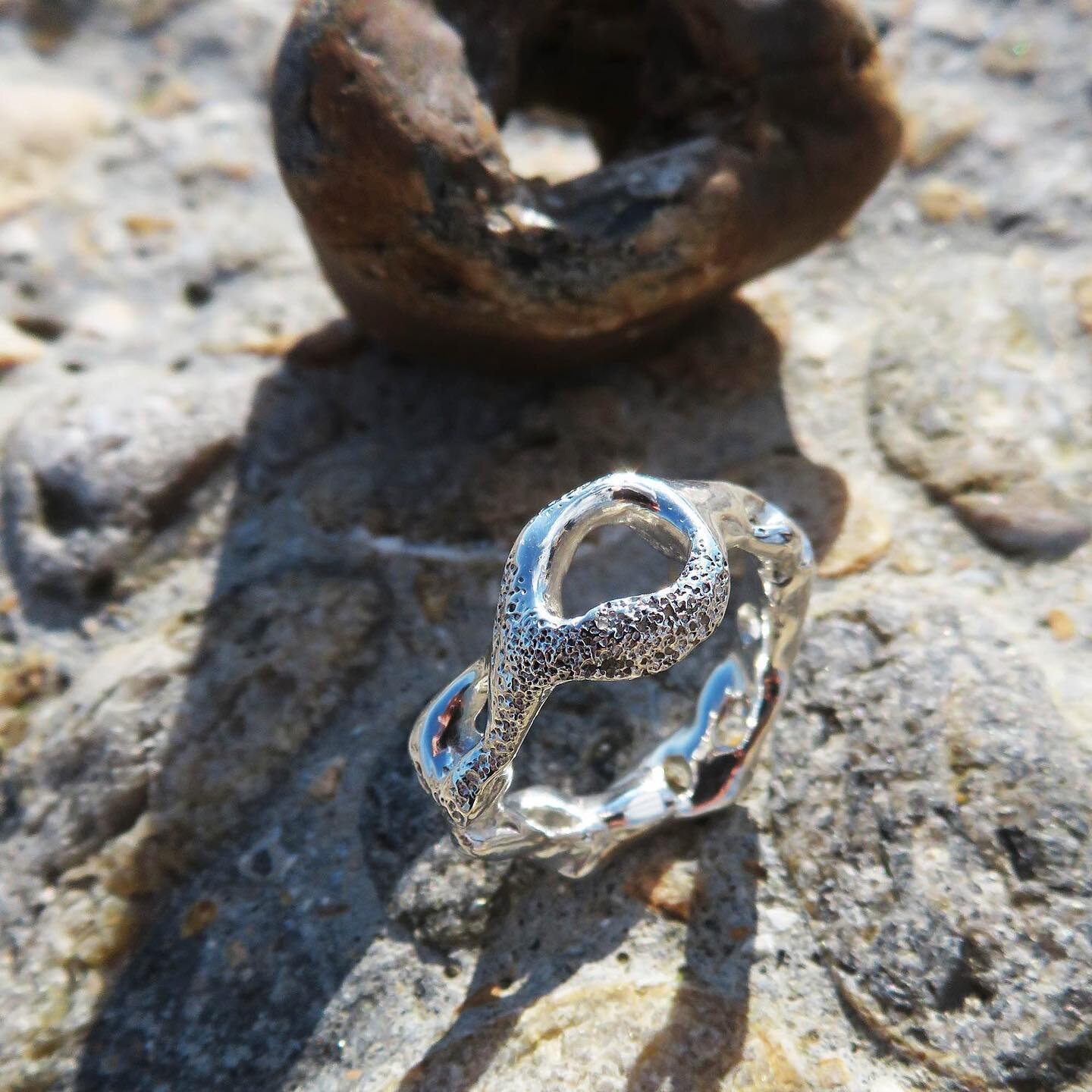 Our one-of-a-kind handmade unisex ring is inspired by the Adder stones - a stone with a naturally occurring hole through it. 

The ring also features a texture created with the help of sand from the beach in the Baltics. 

The sand has been carefully