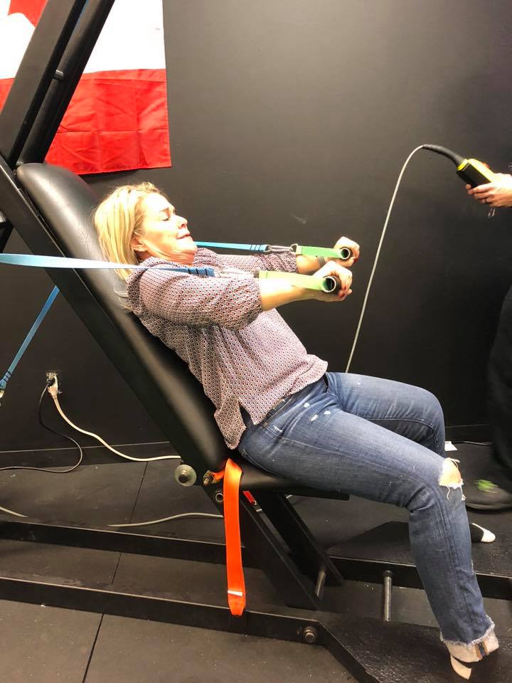 Woman sitting and pulling on innovative health and performance outstrip exercise bands