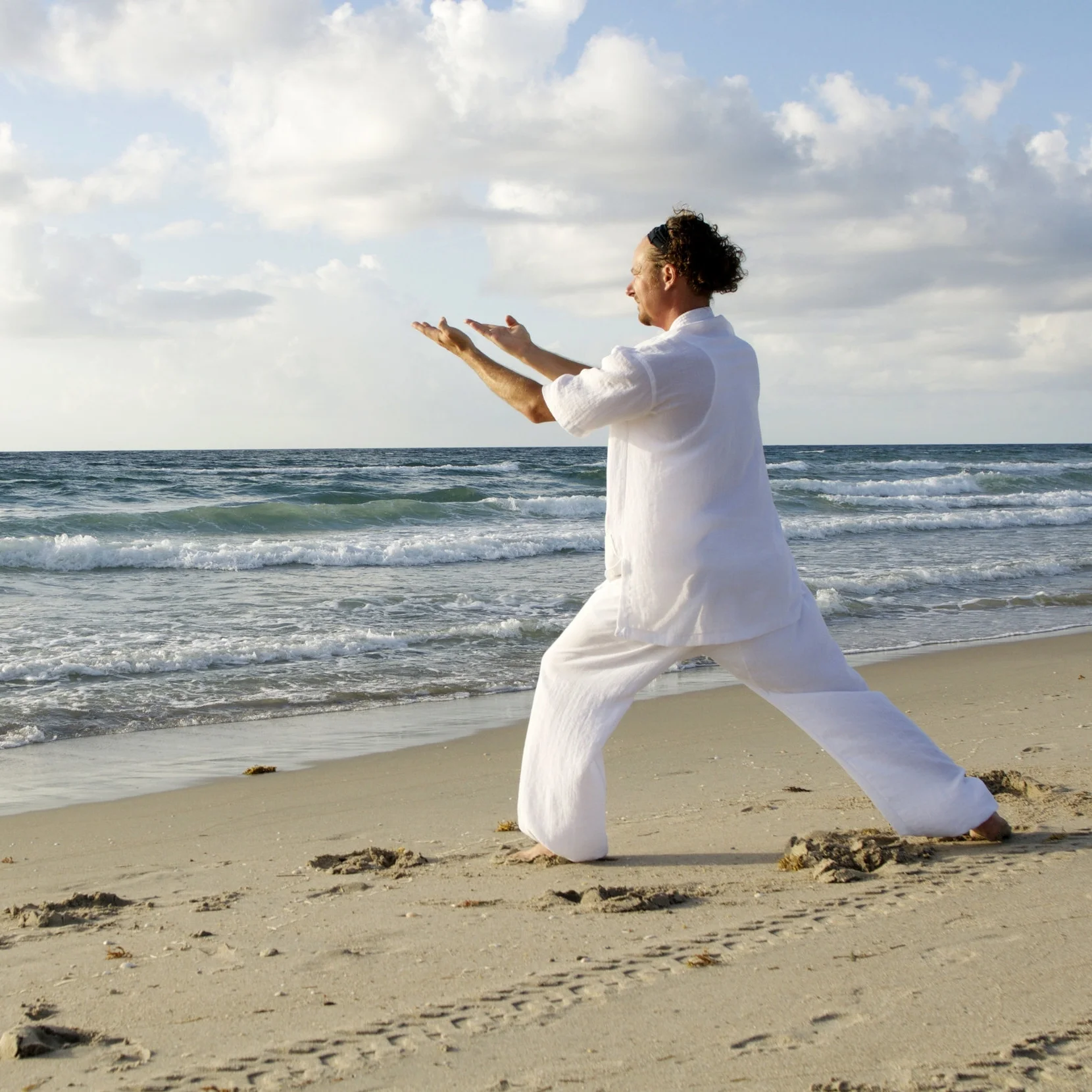man-dressed-in-white-praticing-tai-chi-on-beasch.jpg