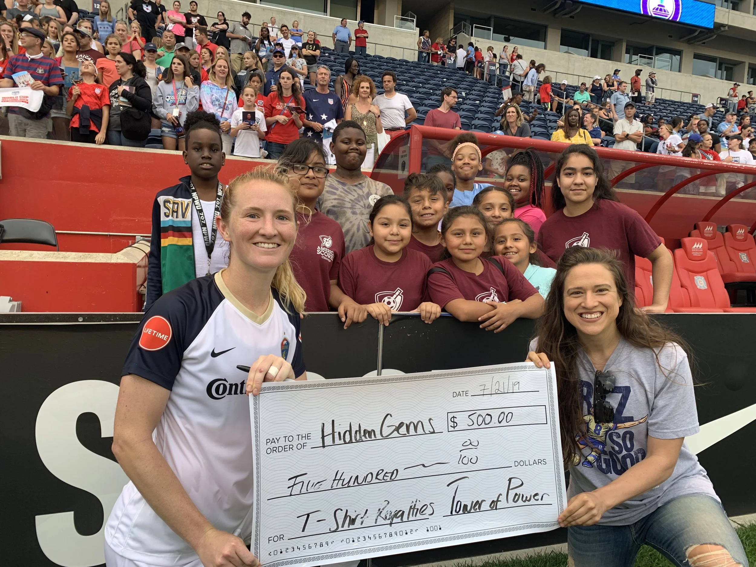 World Cup Champion Sam Mewis presents a check for her $500 donation