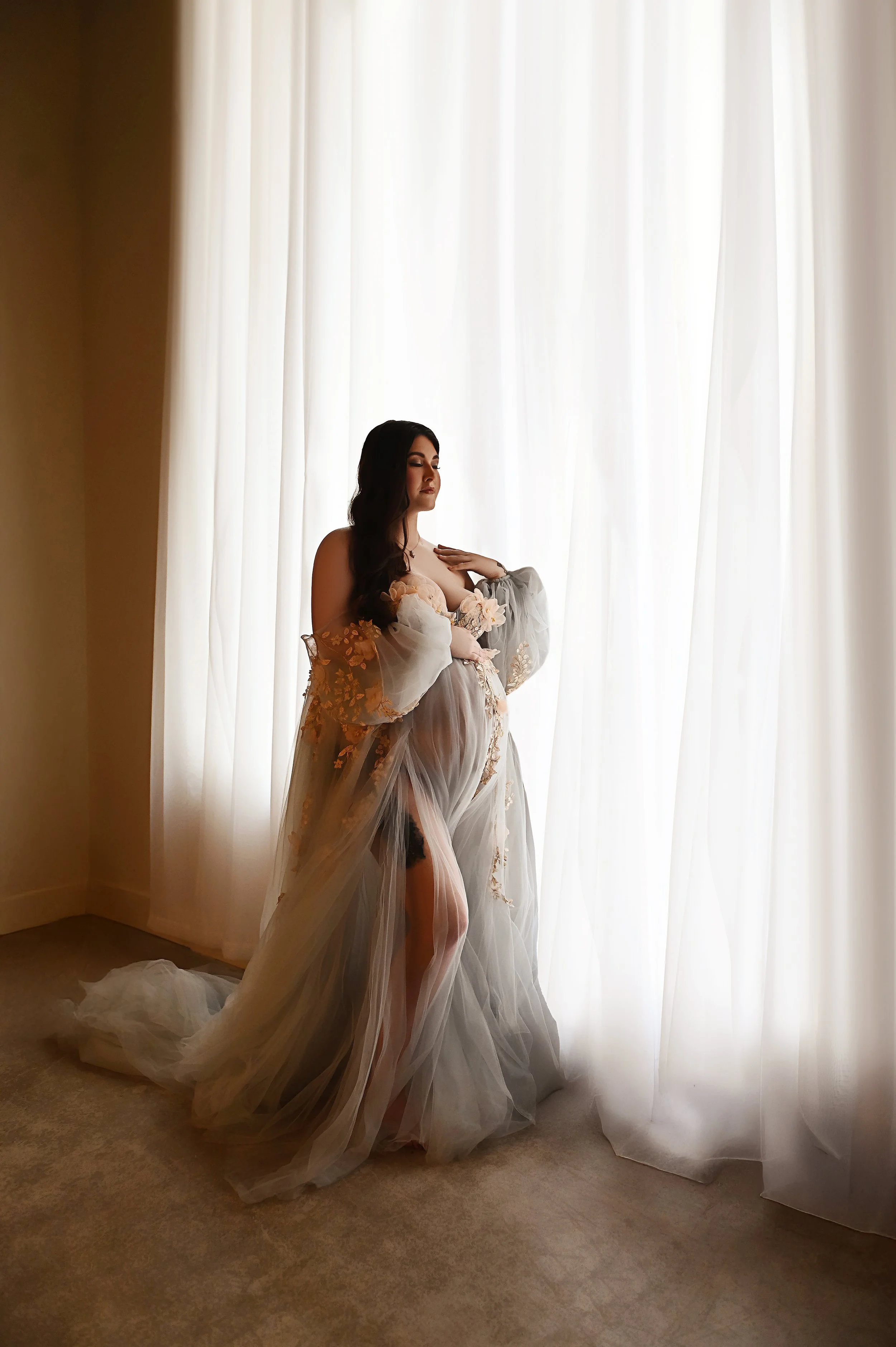 Fine art maternity photography session in Shreveport featuring a pregnant woman in soft window light