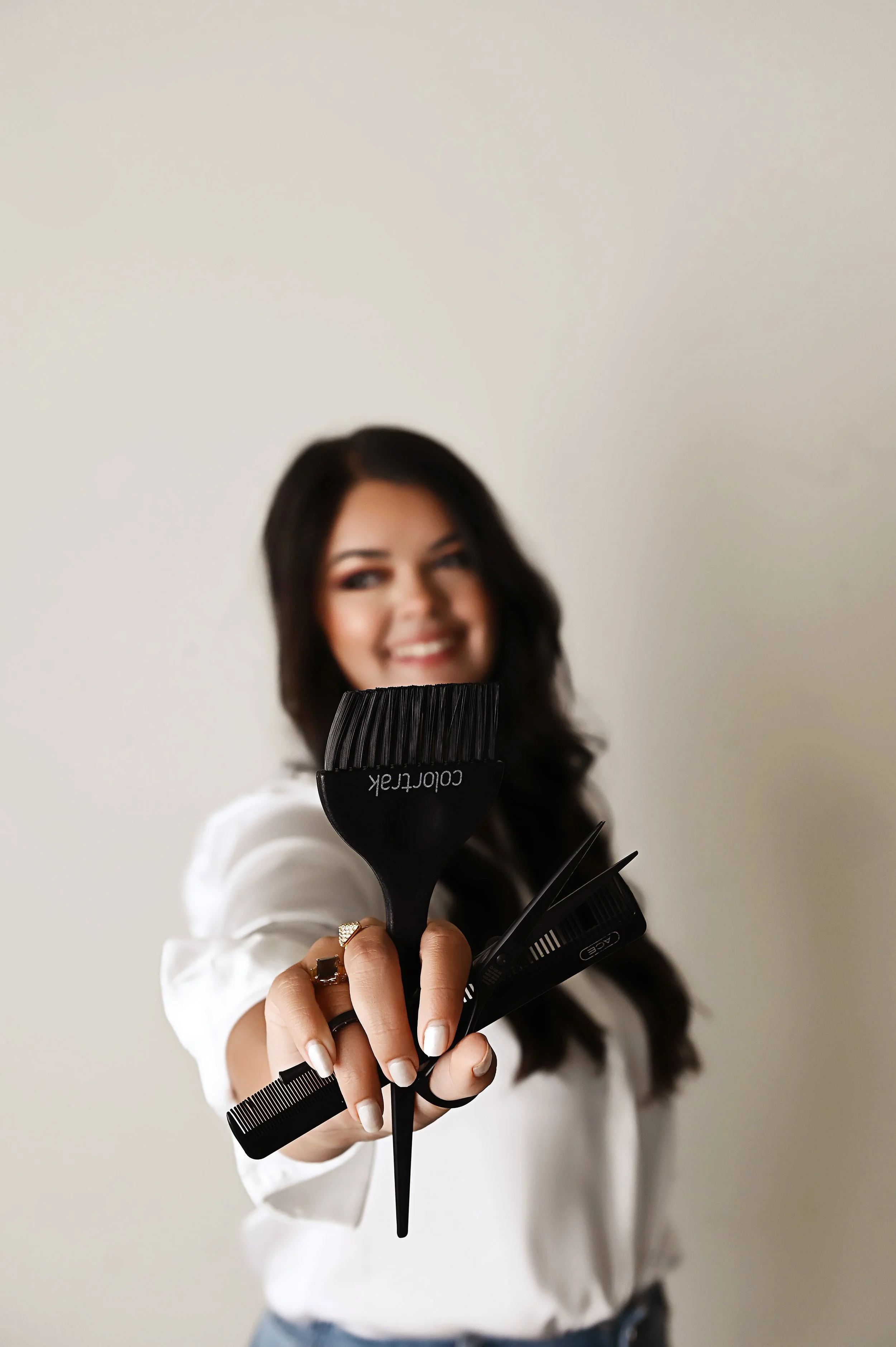 Professional branding portrait of Shreveport hair stylist Britney wearing a white blouse and jeans in a clean studio setting