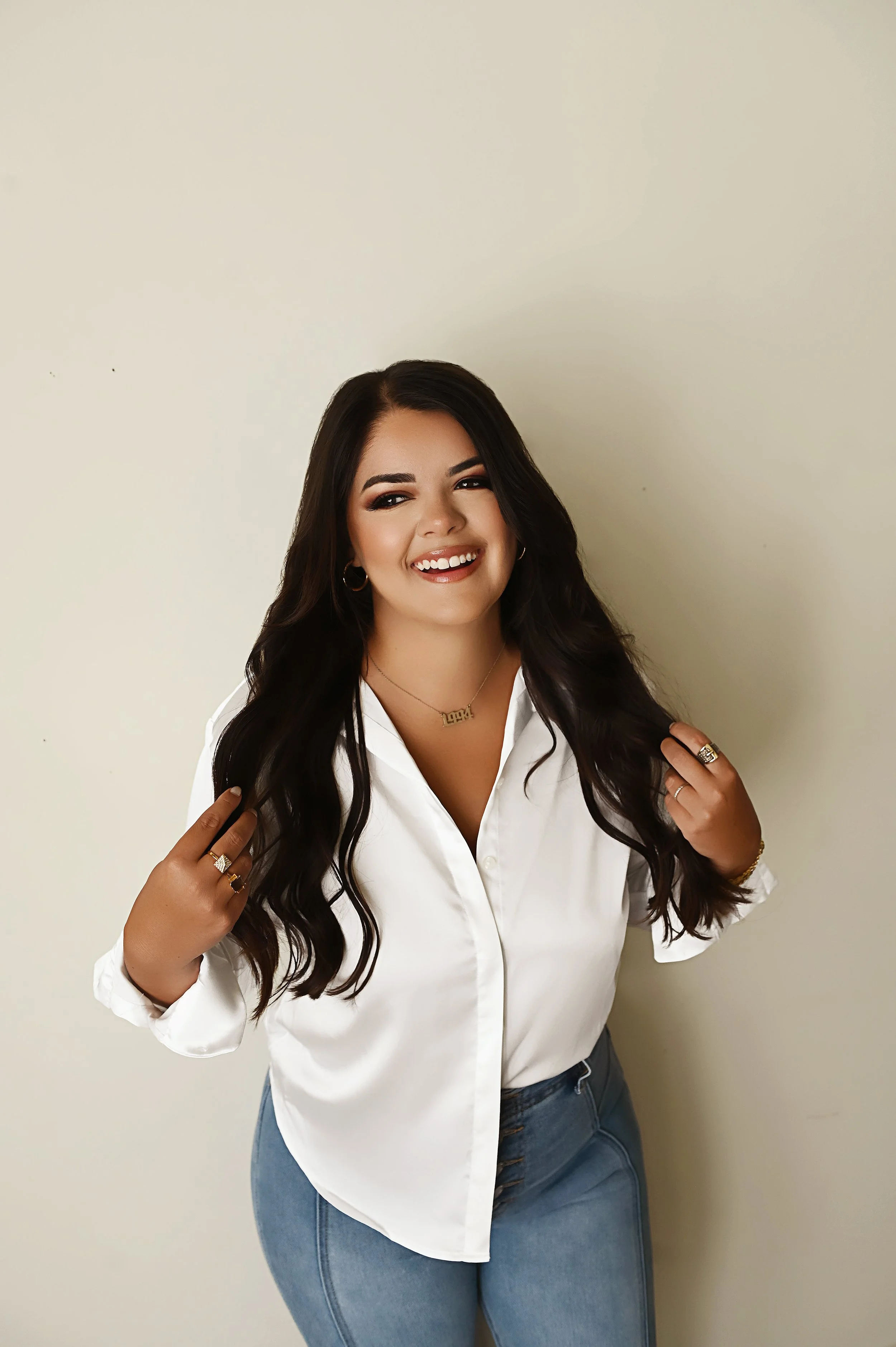 Smiling branding portrait of Shreveport hair stylist Britney against a neutral studio wall