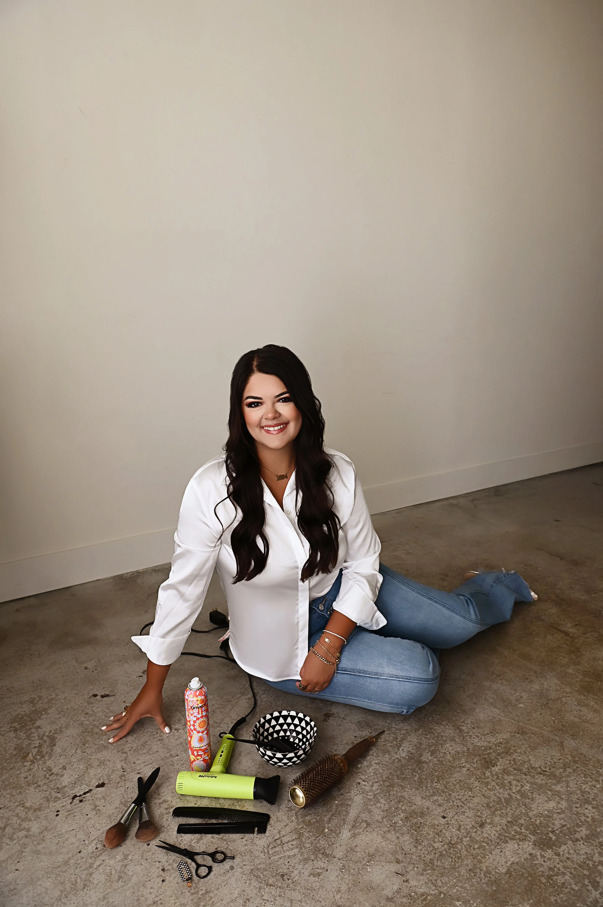 Branding image of Shreveport hair stylist Britney seated with professional hair tools arranged on studio floor