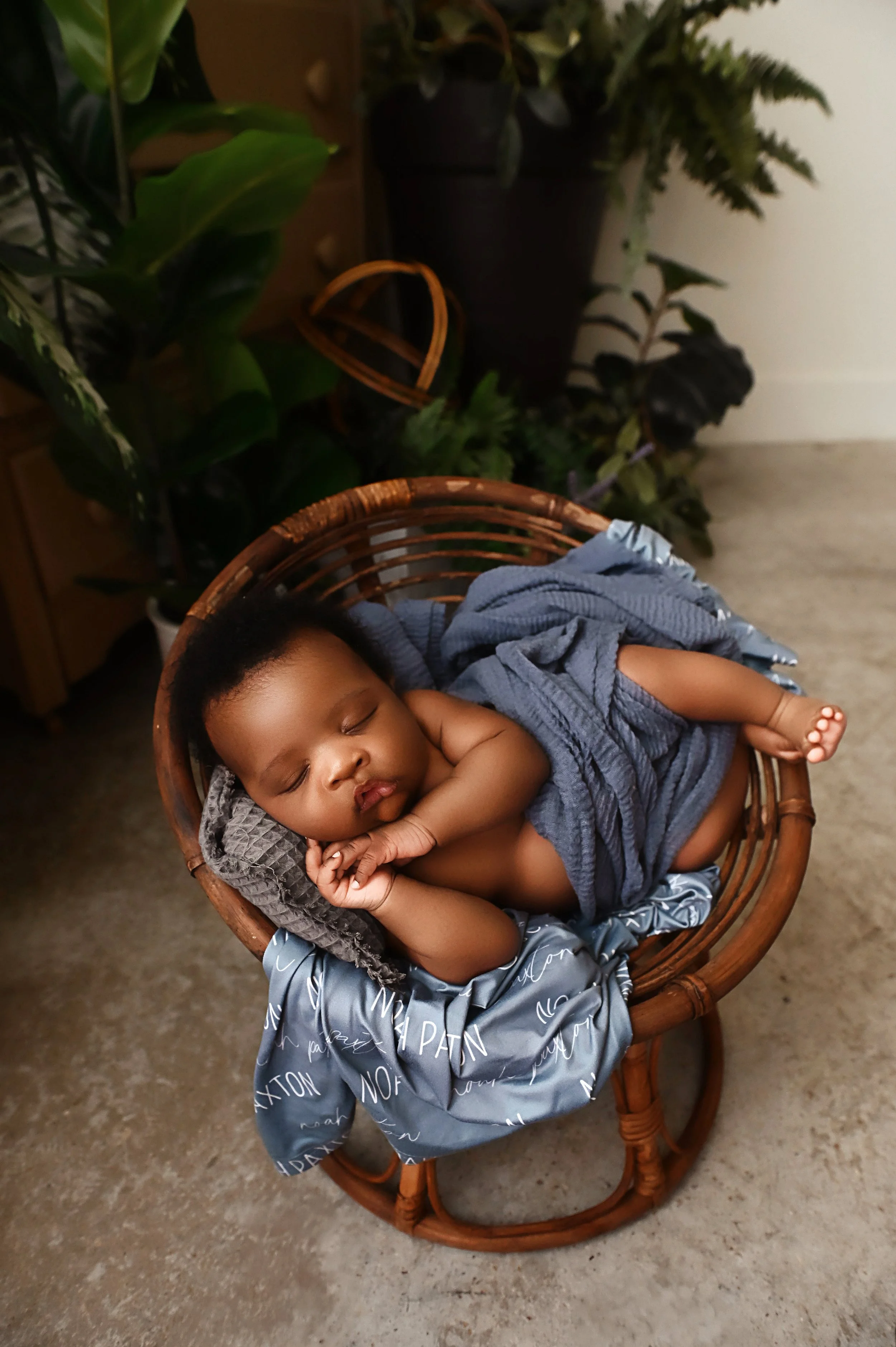 Five week old baby boy sleeping in wicker basket with blue wrap