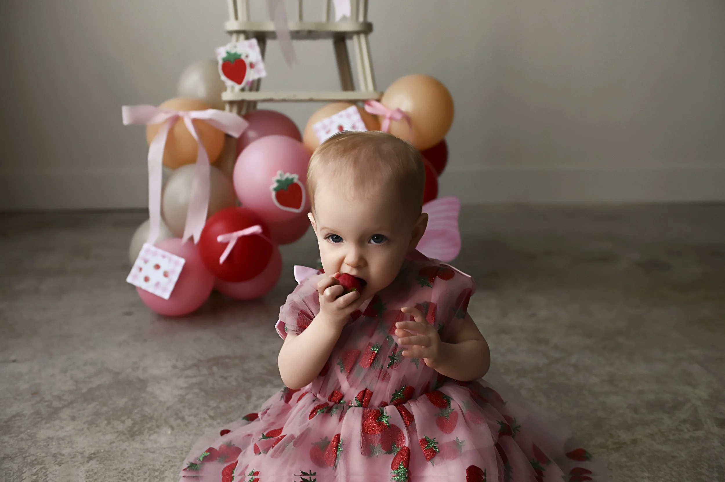 baby girl eating a strawberry during first birthday photo session