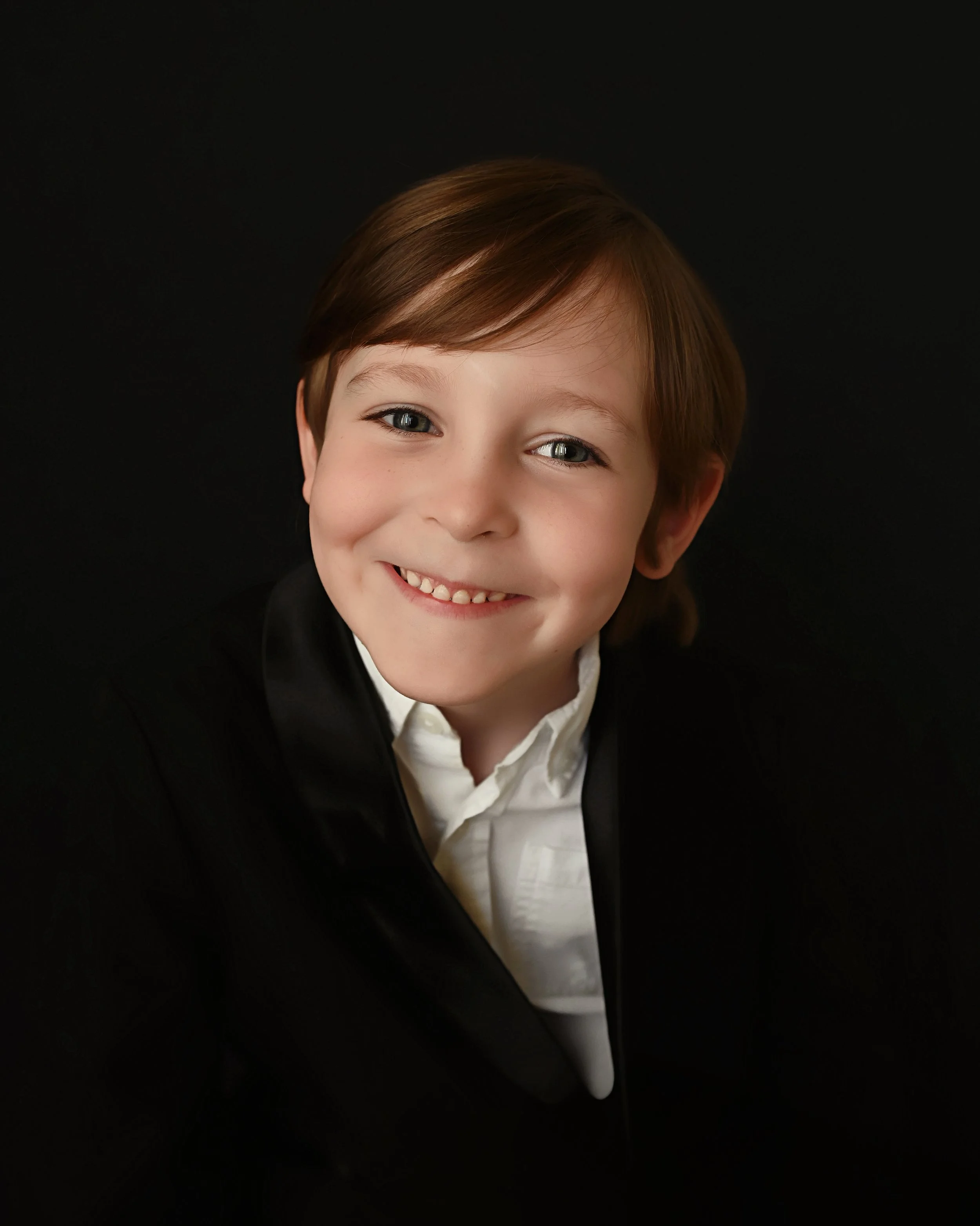 Kindergarten graduation portrait of young boy smiling in studio with black background in Shreveport Louisiana