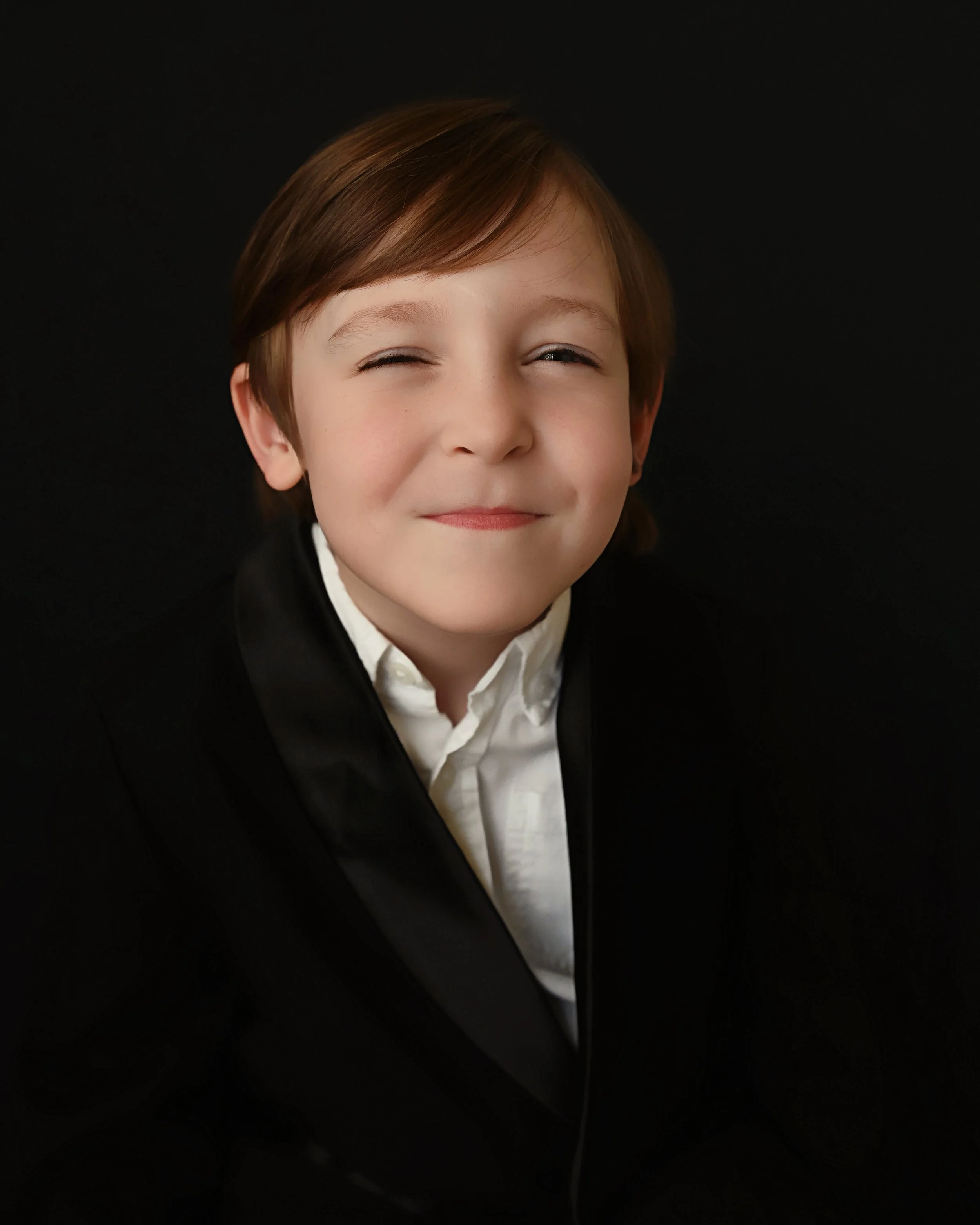 Young boy kindergarten graduate smiling softly during studio portrait session in Shreveport Louisiana