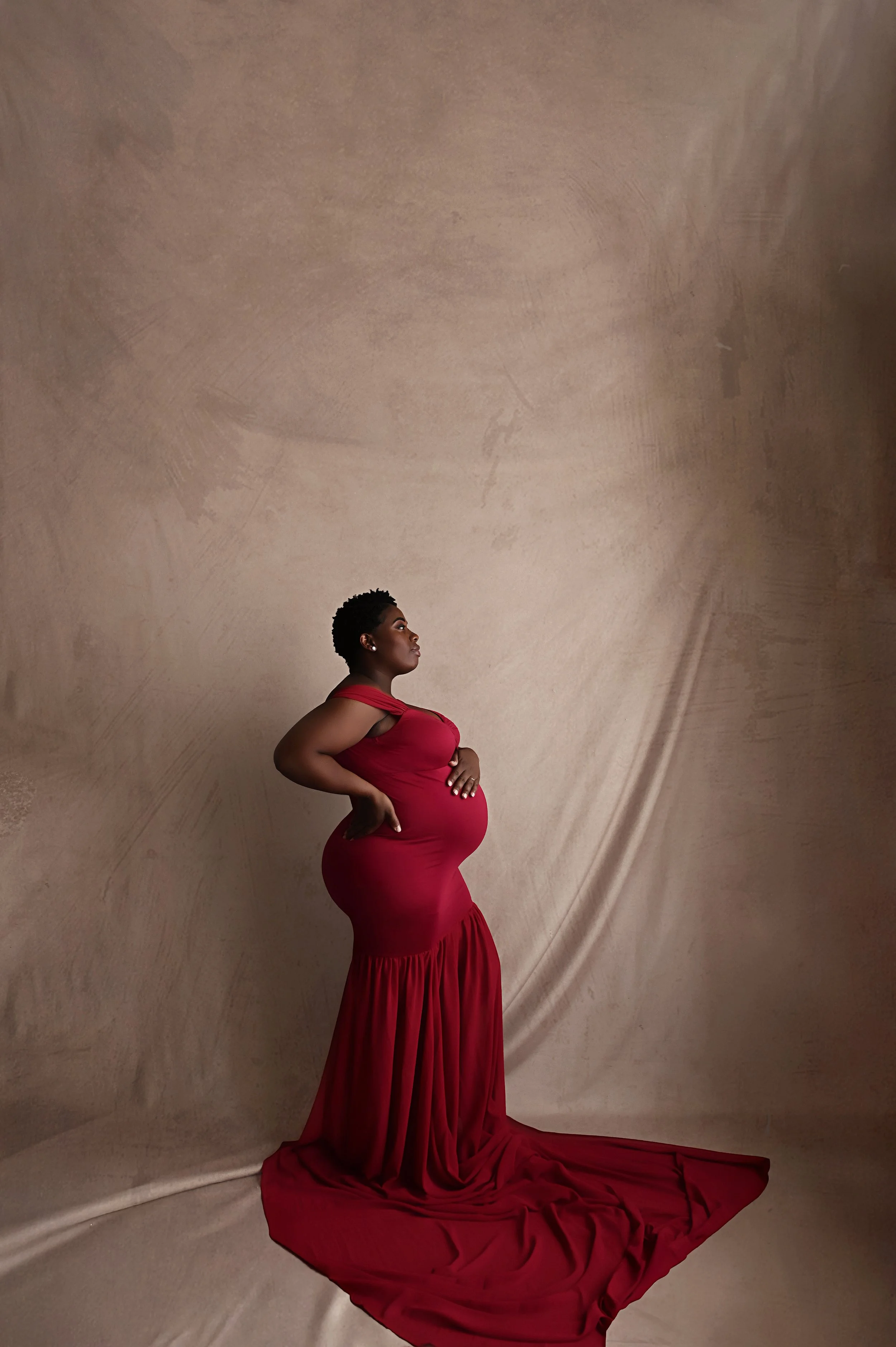 side profile maternity portrait of pregnant mother in fitted red gown during Shreveport maternity photography session