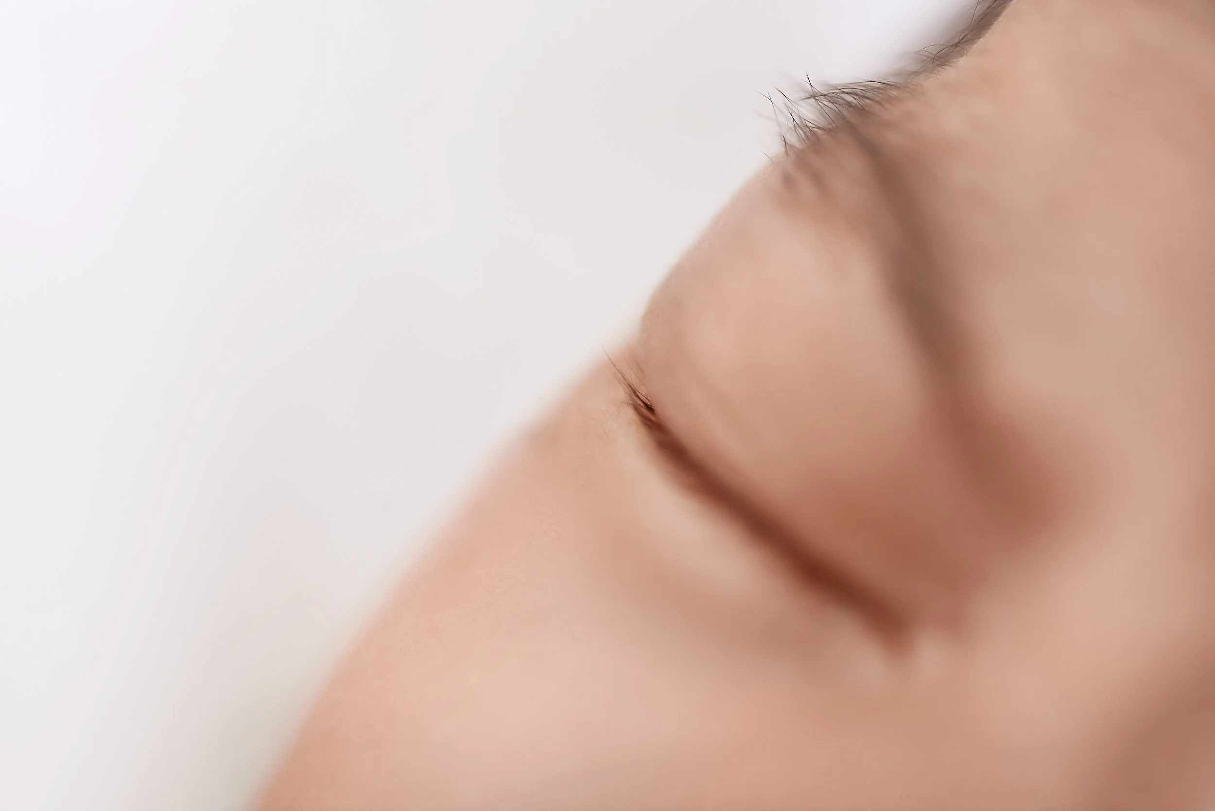 close up photo of newborn eyelashes and closed eye on white backdrop