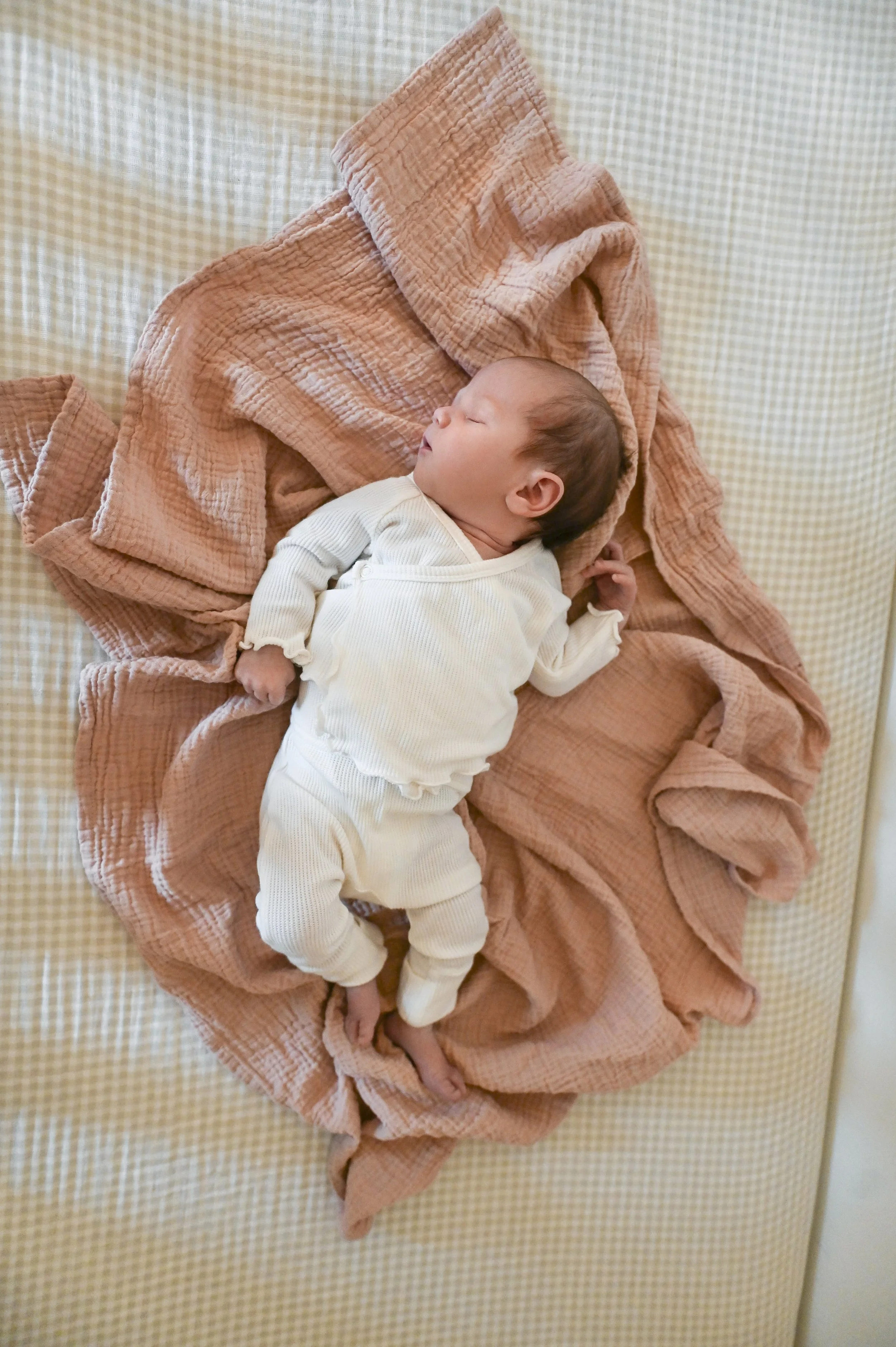 newborn baby laying on soft blanket in natural light at home