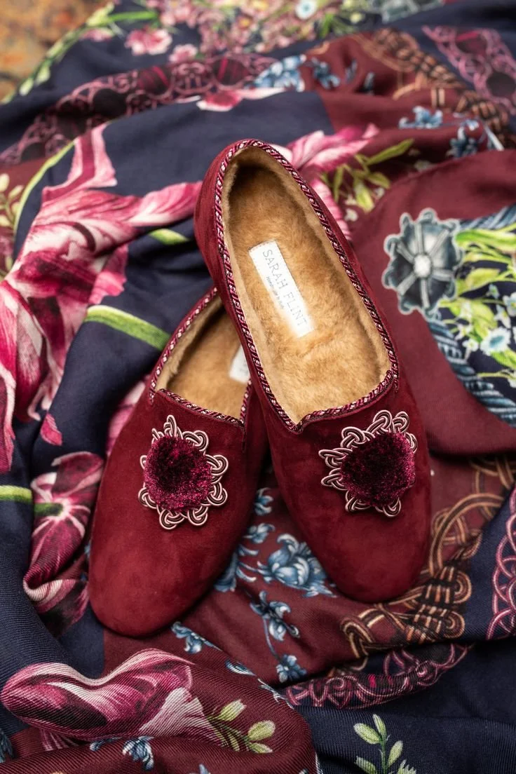 Burgundy shearling slippers with textured rosette detail.jpeg