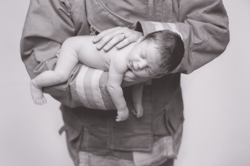 Baby Cooper posing with firefighter dad during baby pictures in San Diego CA