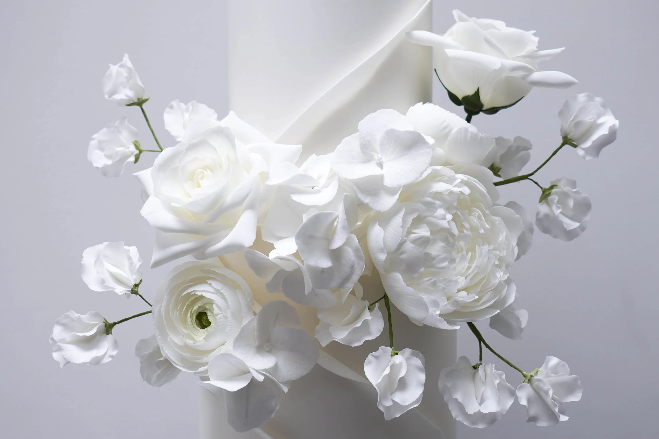 Elegant sculpted white wedding cake by Blossom Tree Cake Company Harrogate, adorned with soft white blooms and delicate foliage, creating a refined, romantic look perfect for Thicket Priory wedding celebrations.