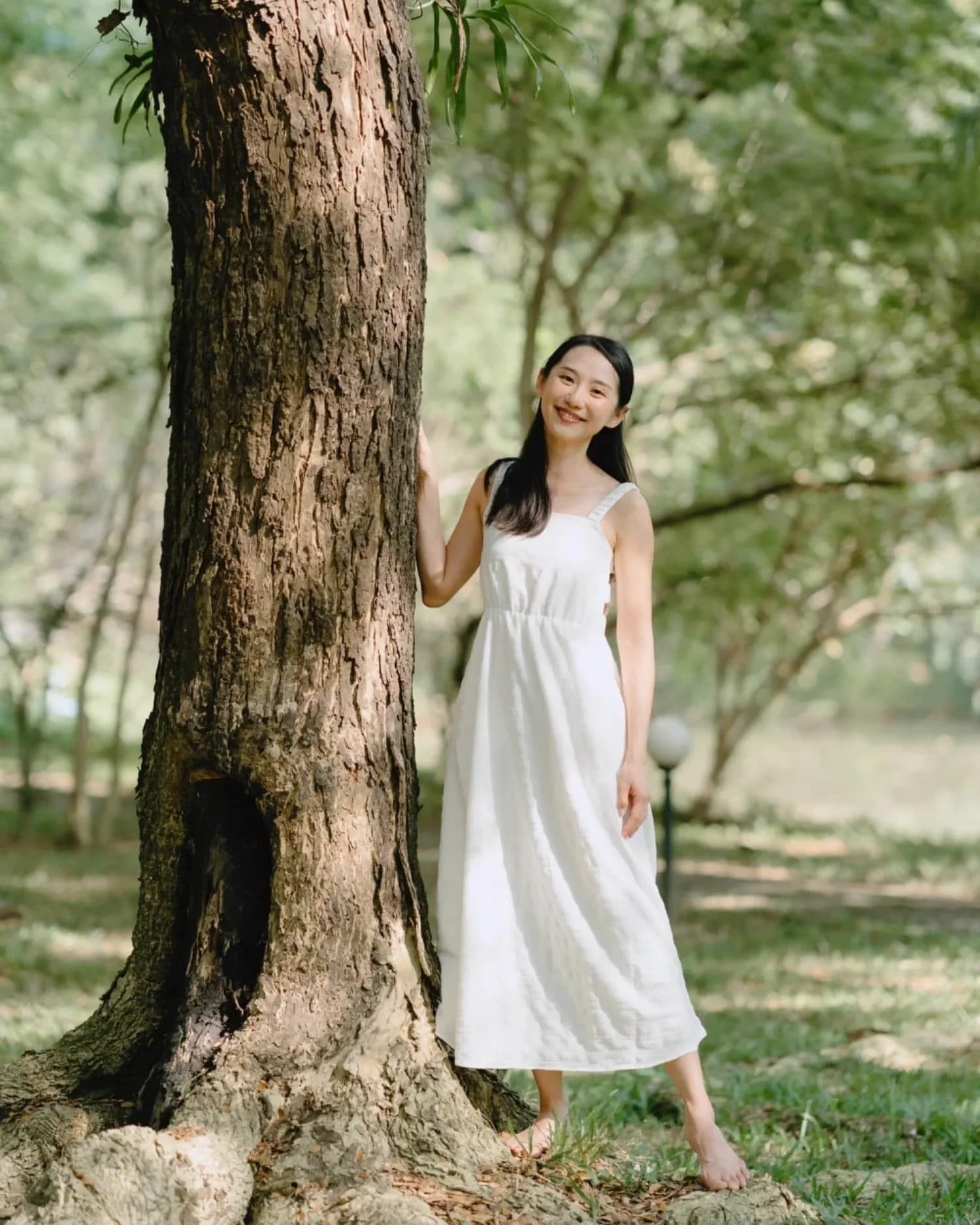 Youmin Yap, ANFT Certified Forest Therapy Guide and Trainer, standing under a large tree.