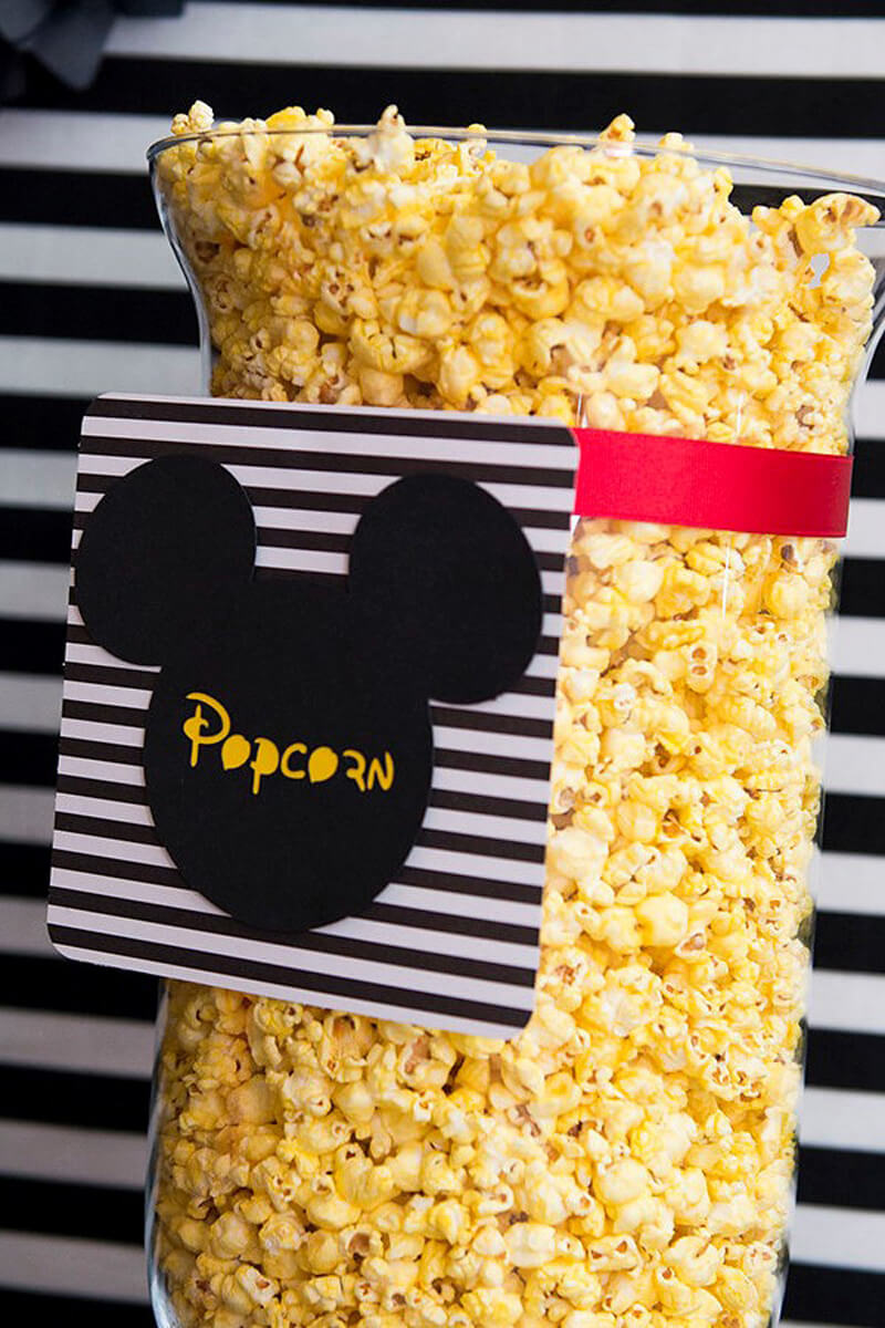 Glass vase full of yellow popcorn, tagged with a mickey printout