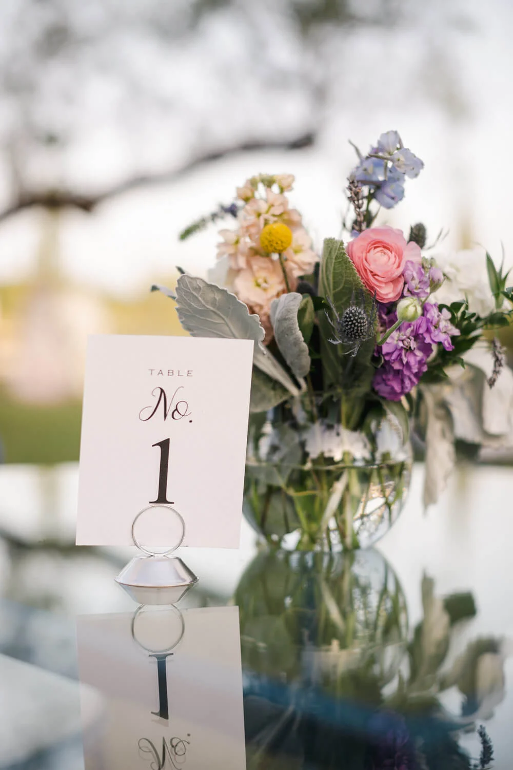 French country wedding inspiration glass table tops with table numbers and flowers.