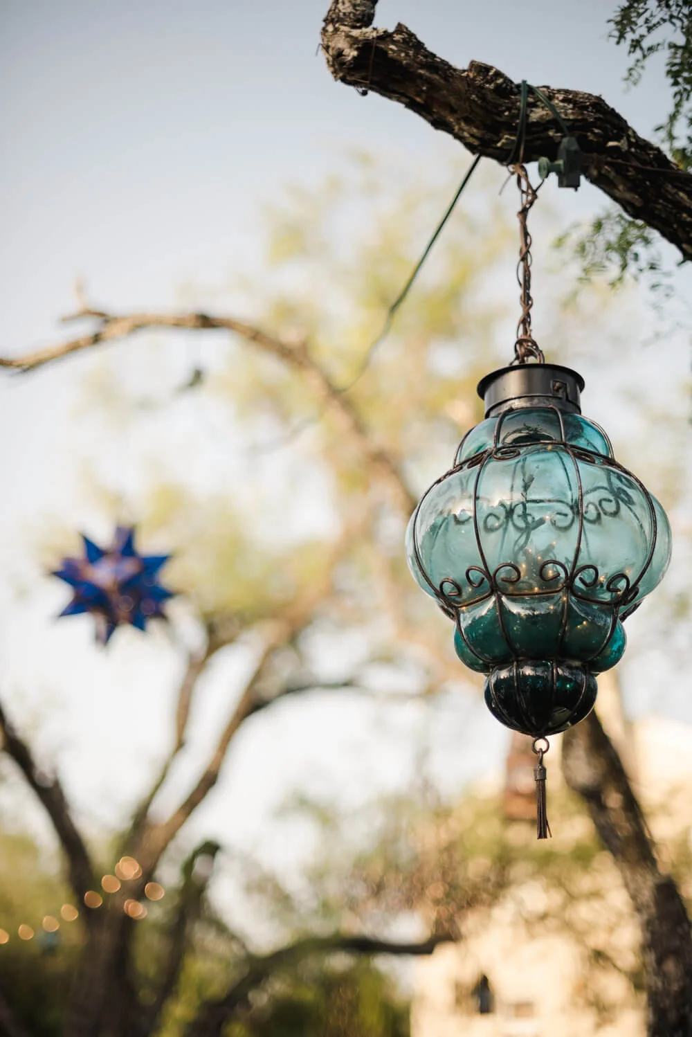 French country wedding inspiration blue glass lanterns hanging from the tree branches.