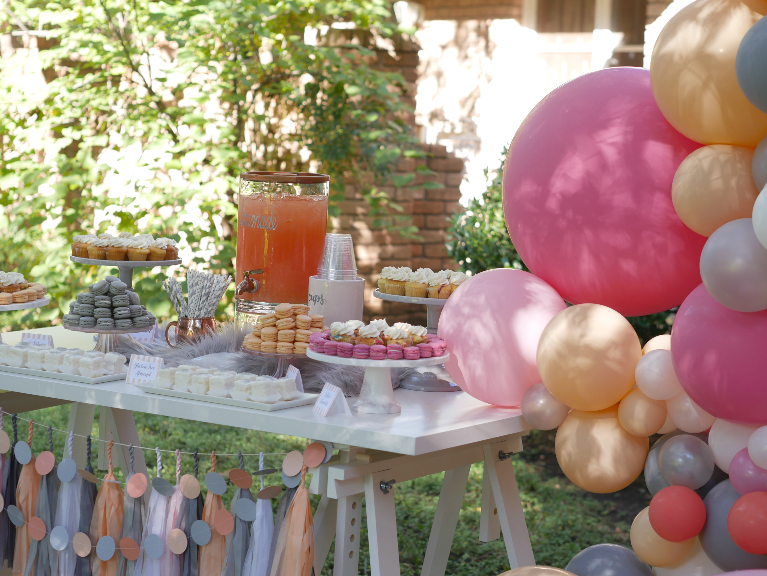 Gray and peach touches on a dessert table, includes a gorgeous balloon garland and a variety of desserts. Styled by Carolina from MINT Event Design i Austin Texas