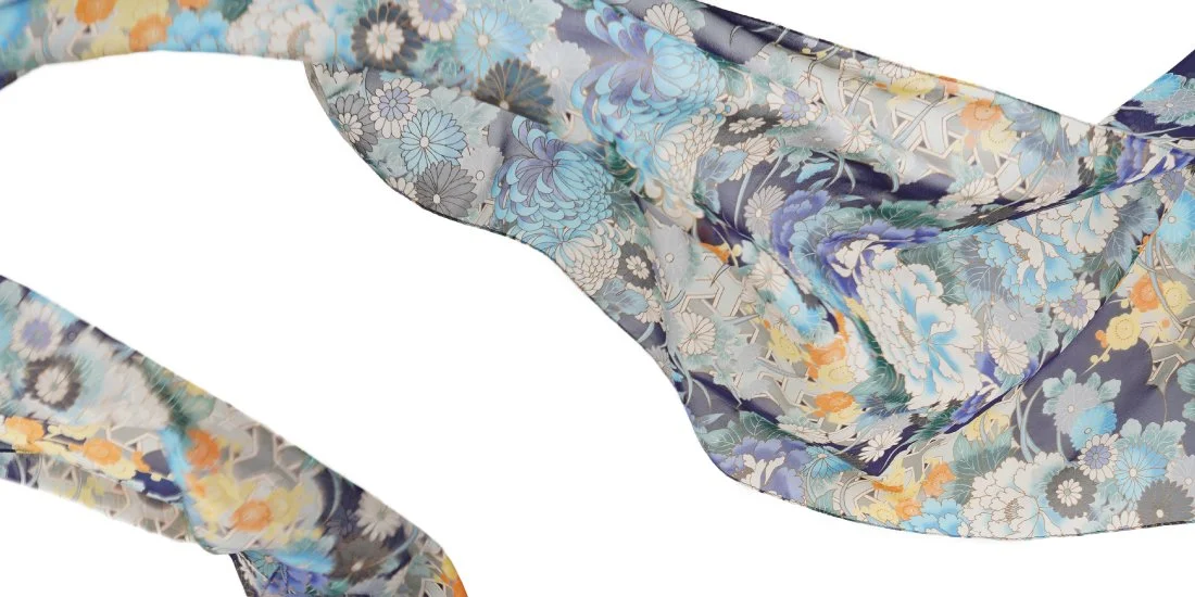 Close-up of a silk fabric with a floral pattern in shades of blue, gray, yellow, and white.