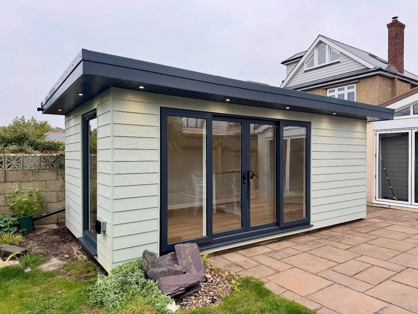Garden Room completed in Poole, roughly 5m x 3m, inline sliding doors with a full height tilt and turn window. Finished with soft green Hardie Plank. #gardenroom #gardenbuilding #gardengym #gardenoffice #gardenstudio