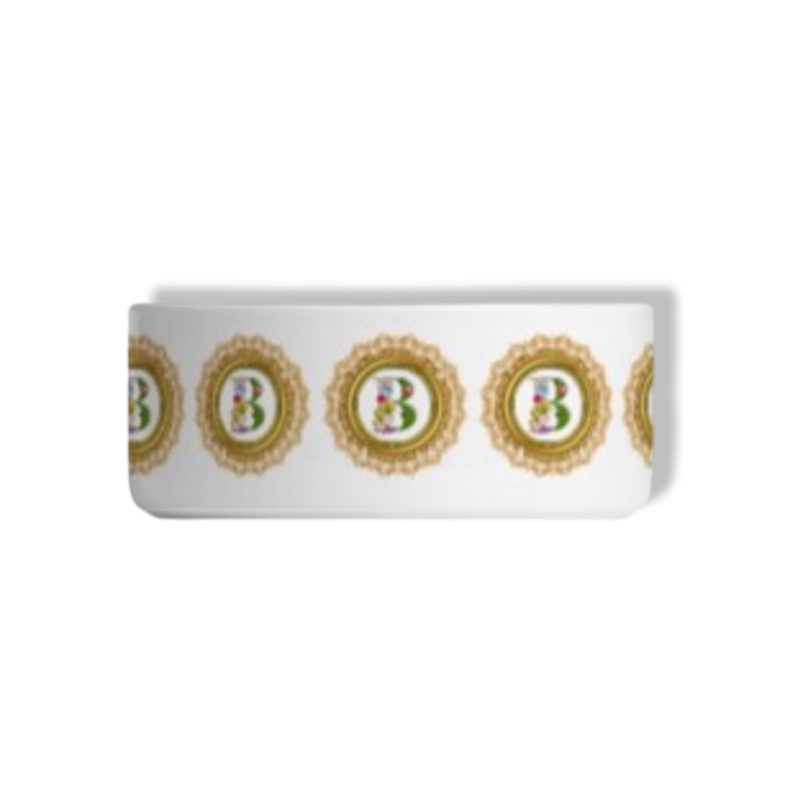Close-up of a white ceramic bowl decorated with a repeating pattern of ornate gold circles, each containing a stylized letter 'B' with floral accents.