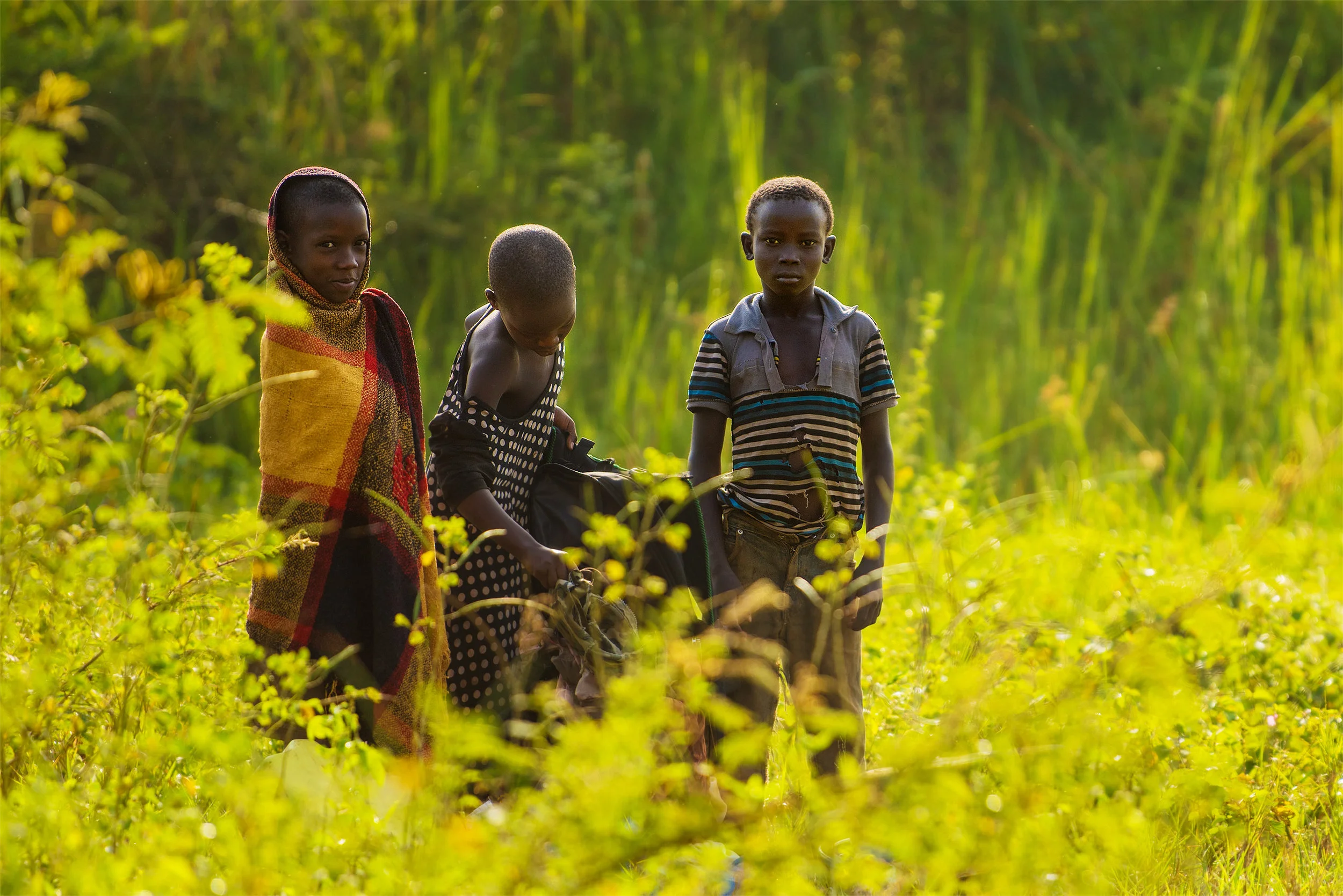 A trio of Ugandan children collect water in Lugogo Swamp.
