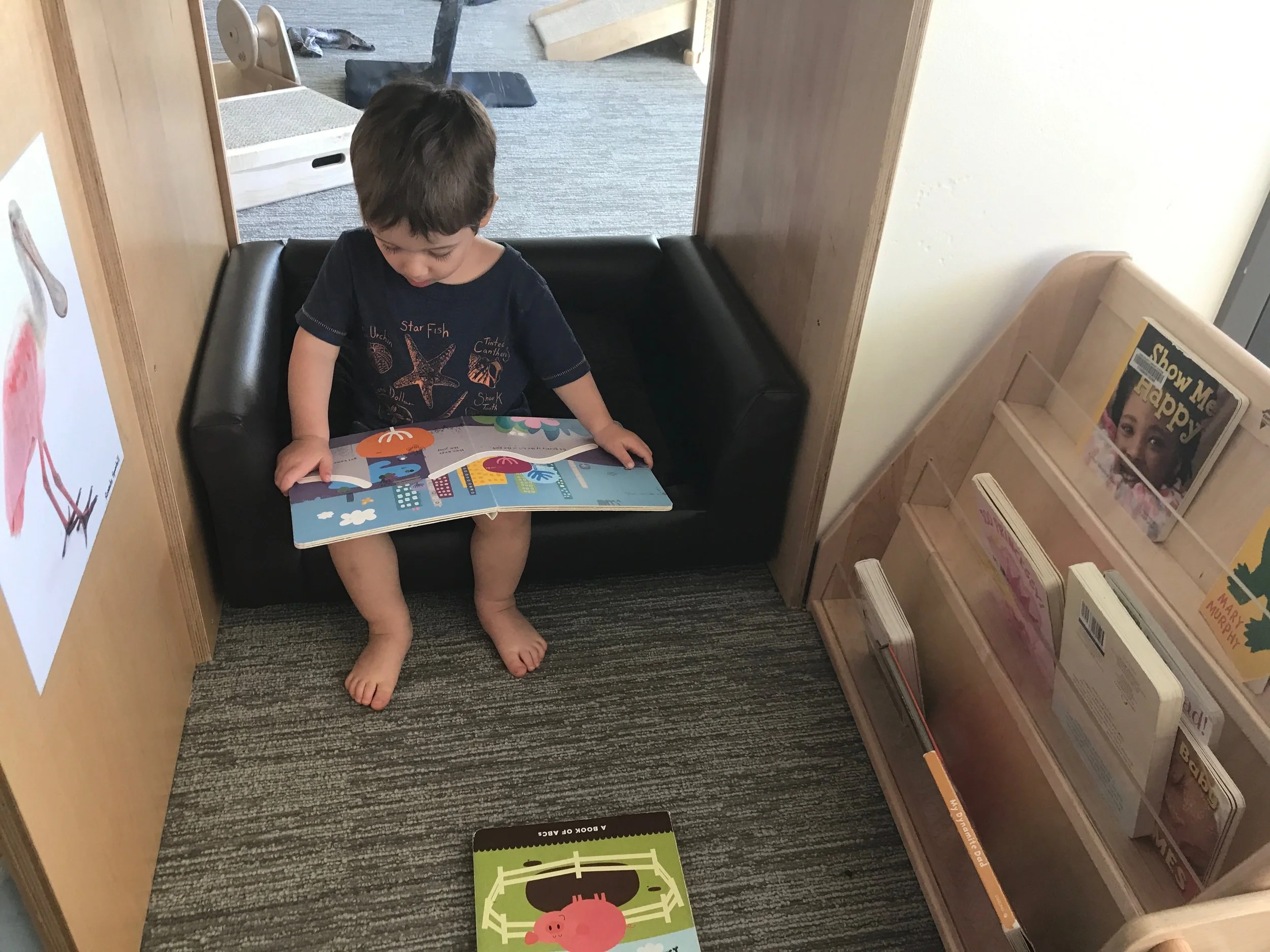 Jackson reading in a window-cubby at daycare. June 30, 2017.