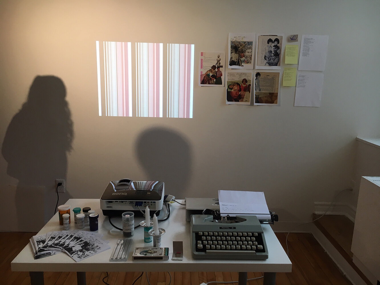 An installation of the preliminary material research for this booklet. On the wall at the top right of the image are digital collages of photographs of my mother, on the table are experimental zines with more collages, my trusty typewriter, shabbos …