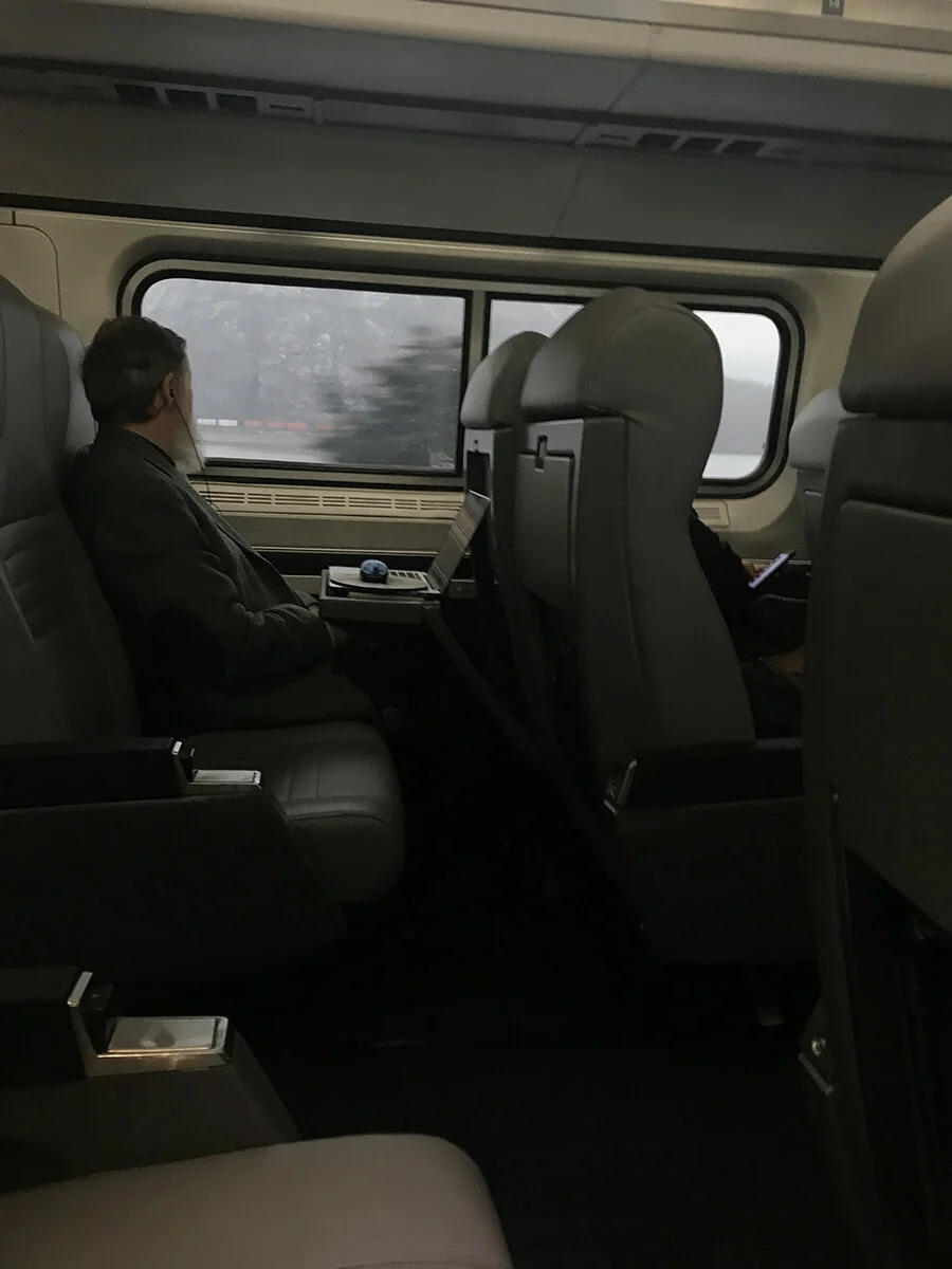 This man across the aisle from me was using the train as his mobile office as well, but he appears distracted by another train passing across the Hudson River, seen out the window. I was able to use my laptop if needed, but I could also complete sma…