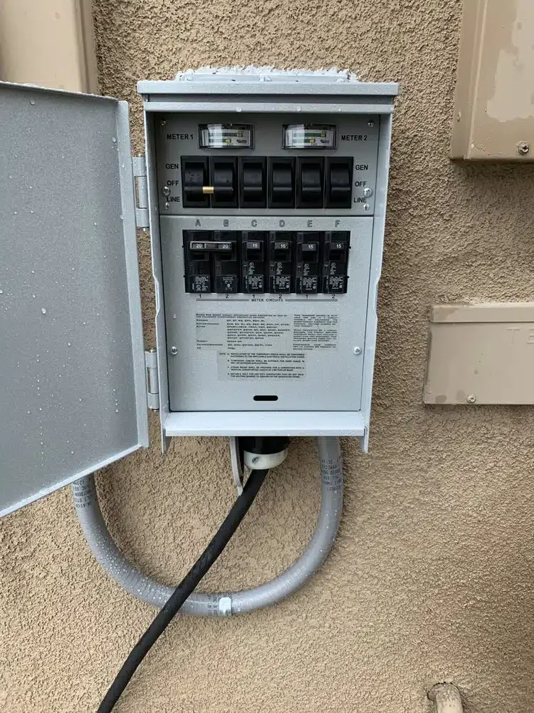 Electrical meter box mounted on a beige exterior wall with an open door, showing circuit breakers and meters inside, connected by conduit and cables.
