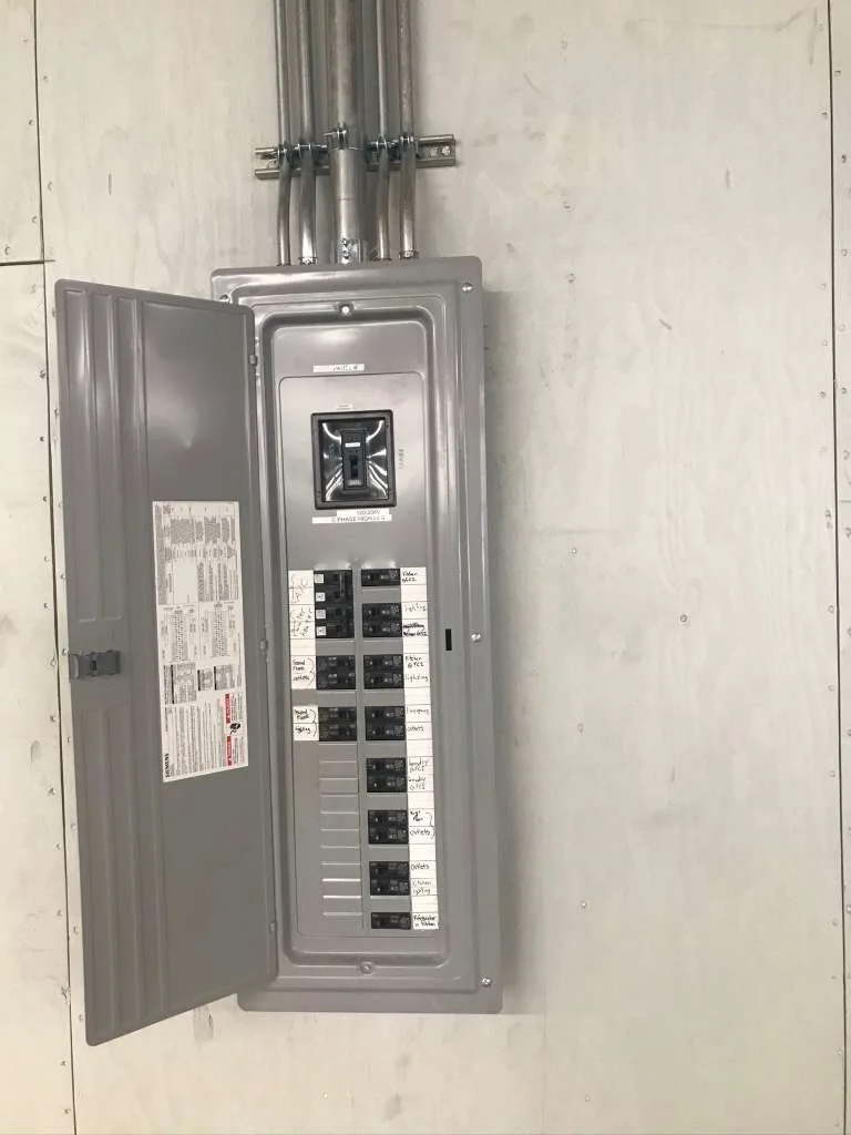 Electrical breaker box with an open door, mounted on a light-colored wall.
