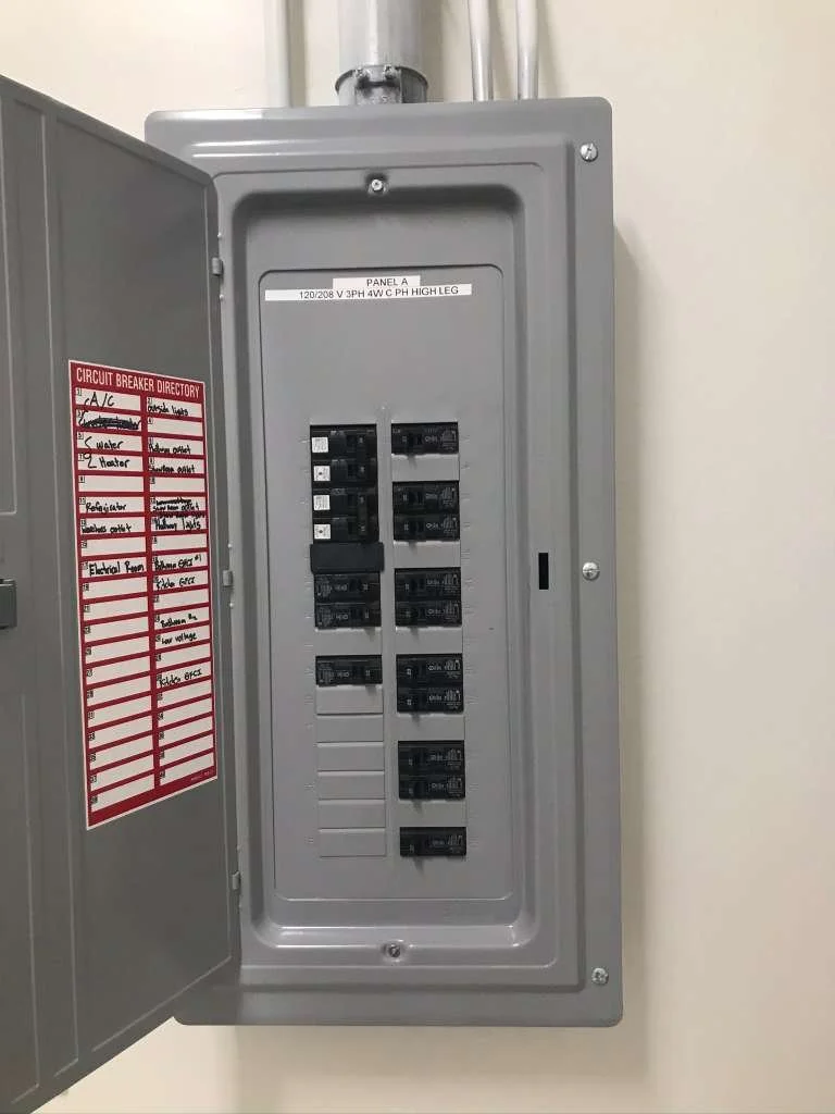 Electric breaker panel with open door, showing circuit breakers and a circuit breaker directory label.