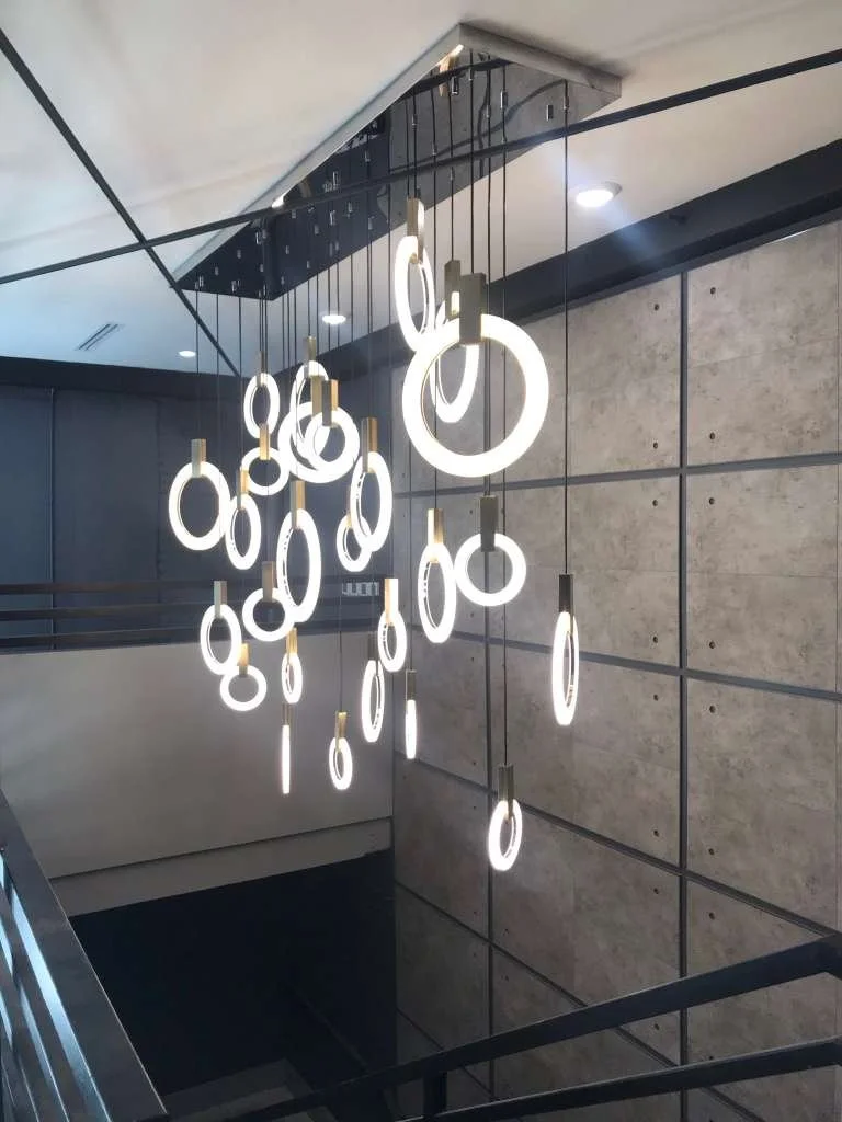 Modern chandelier with multiple circular LED lights hanging from the ceiling of a building interior.