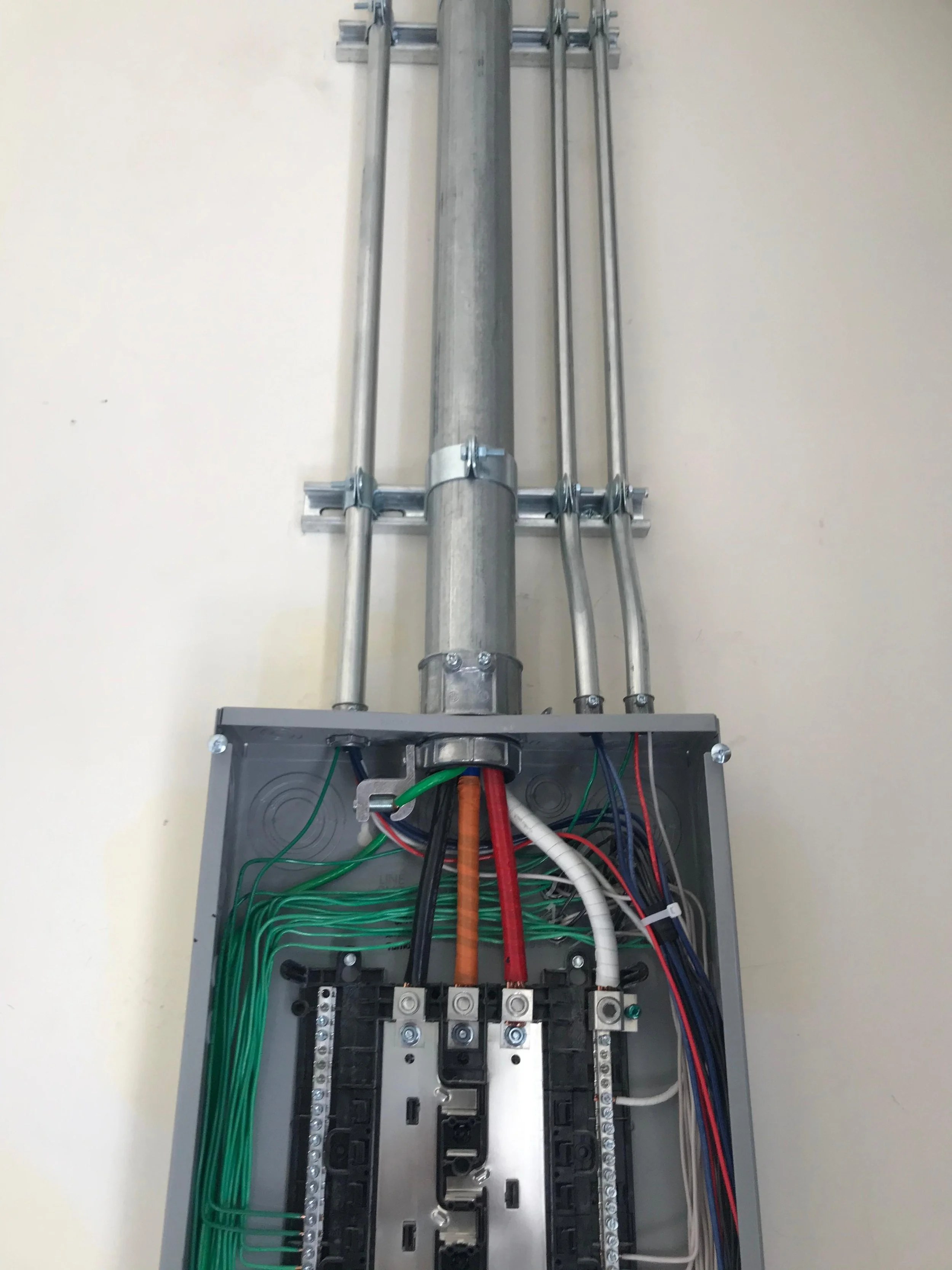 Electrical conduit and wiring inside an electrical control panel.