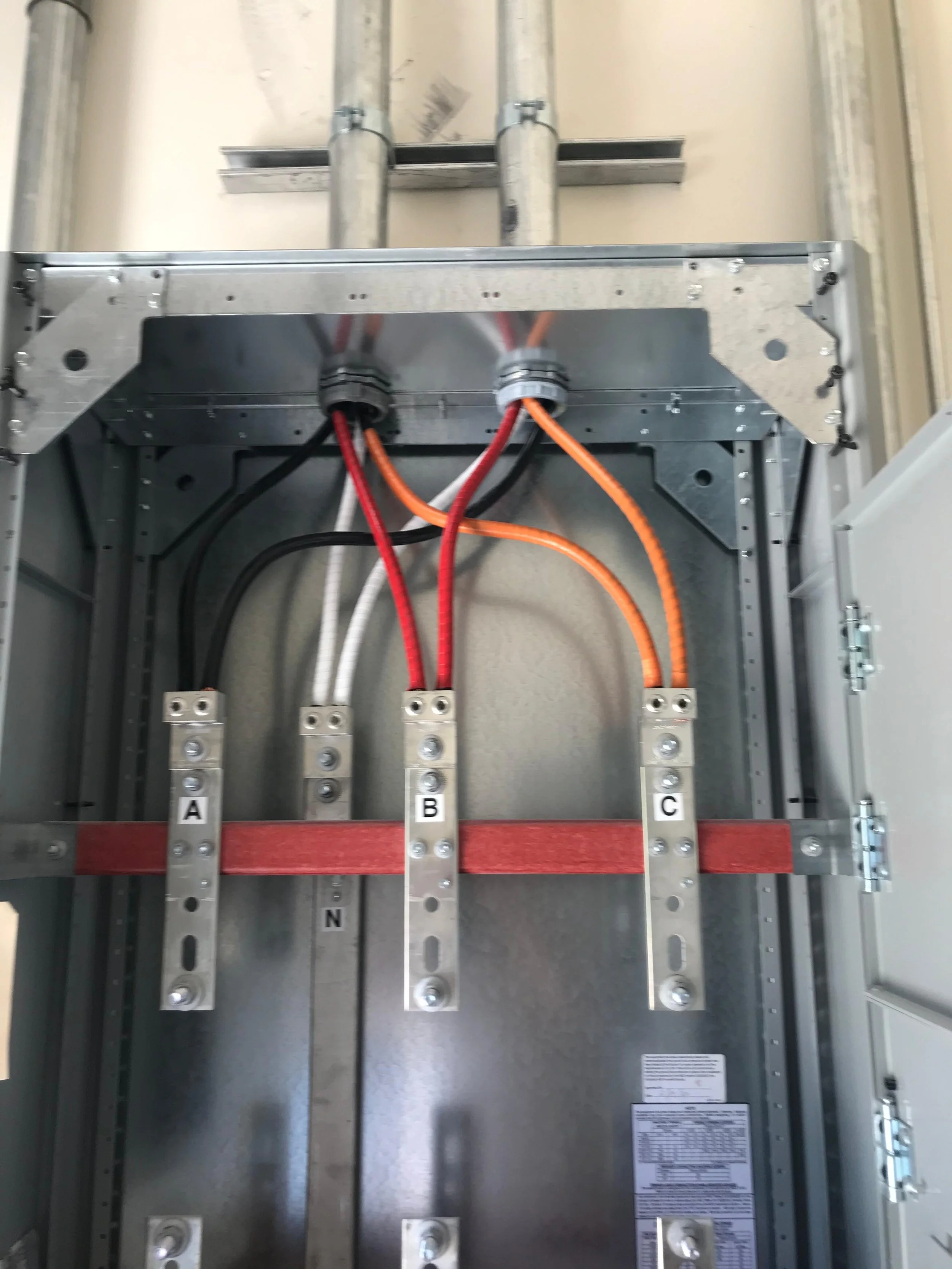 Electrical panel with four labeled bus bars, labeled A, B, C, and N, with colored wires connected to each bus bar.