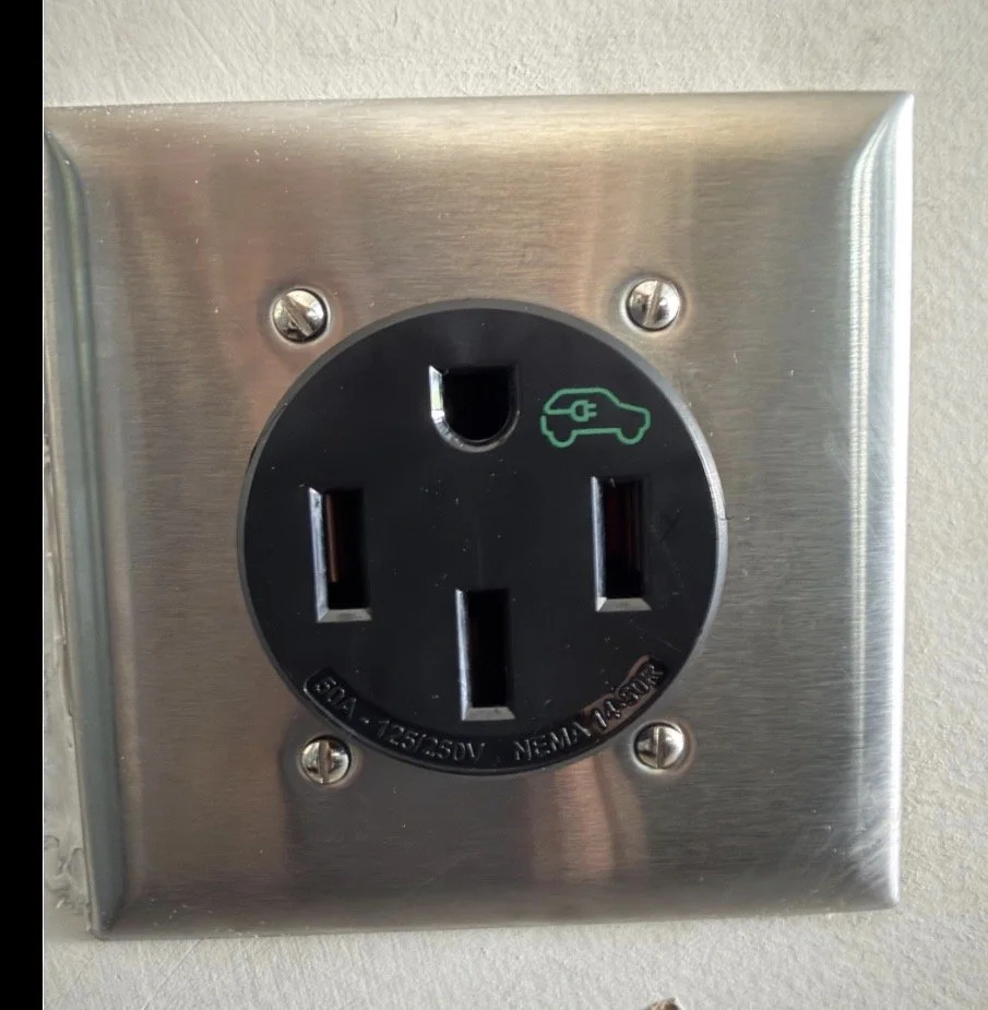Electrical outlet with a green car charging symbol on it, indicating it is an electric vehicle charging outlet.