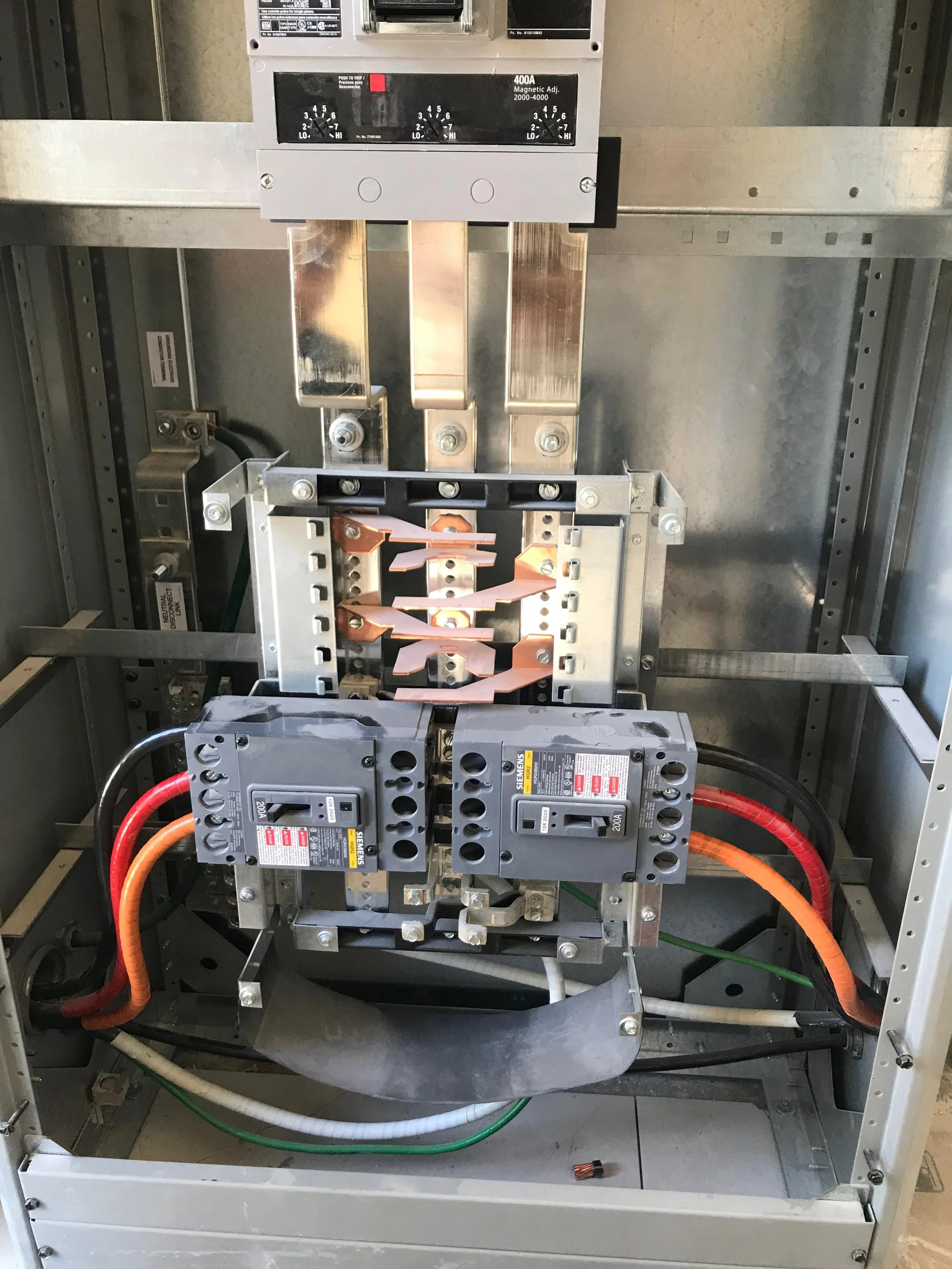 Electrical power distribution box with circuit breakers, wiring, and a metal enclosure.