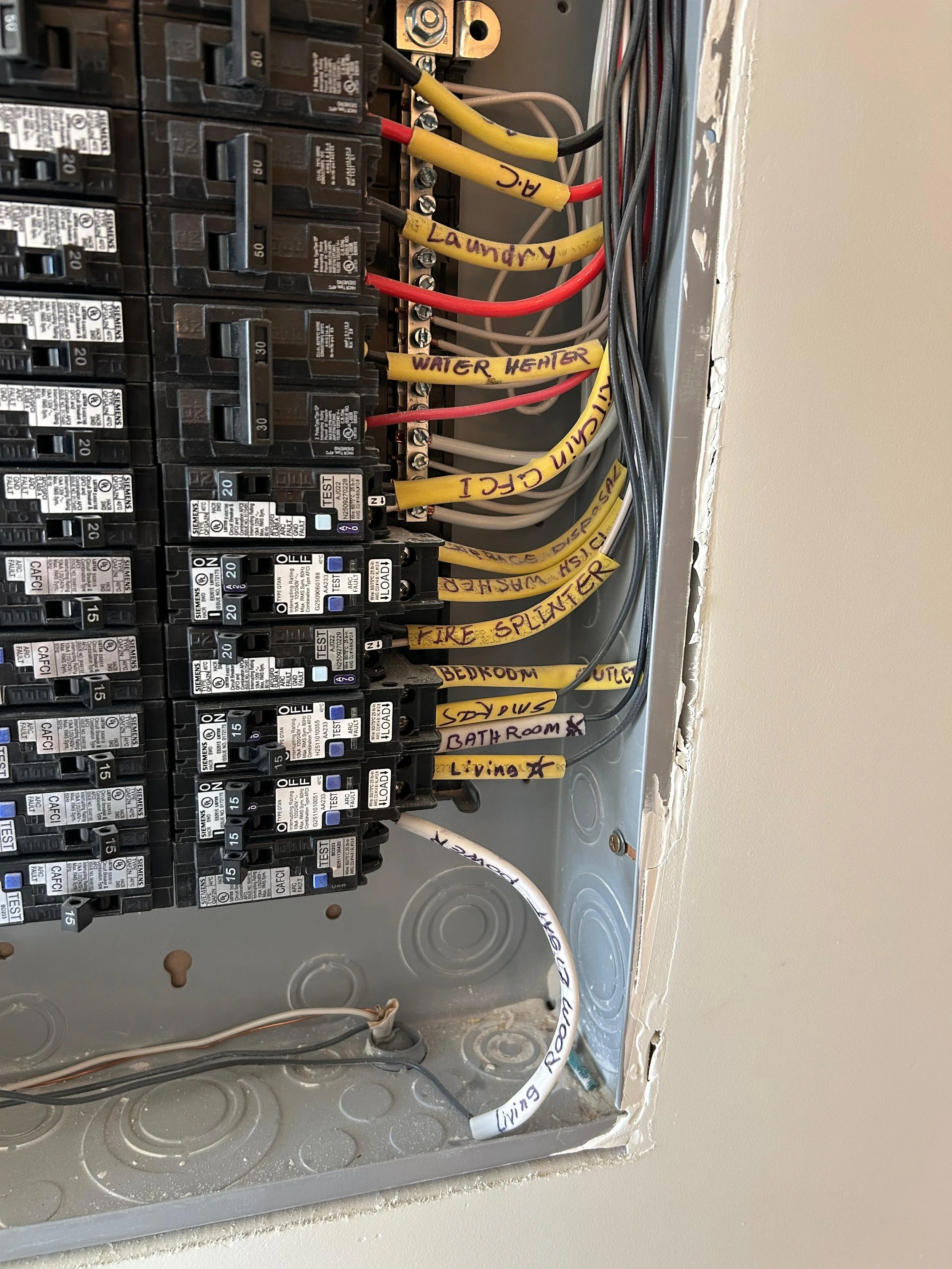 Electrical breaker panel with labeled wires including laundry, water heater, bathroom, living, living room, kitchen, and fire sprinkler.
