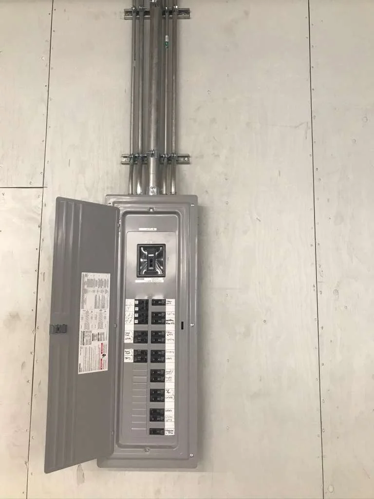 Electrical breaker panel with an open door, mounted on a plain wall.
