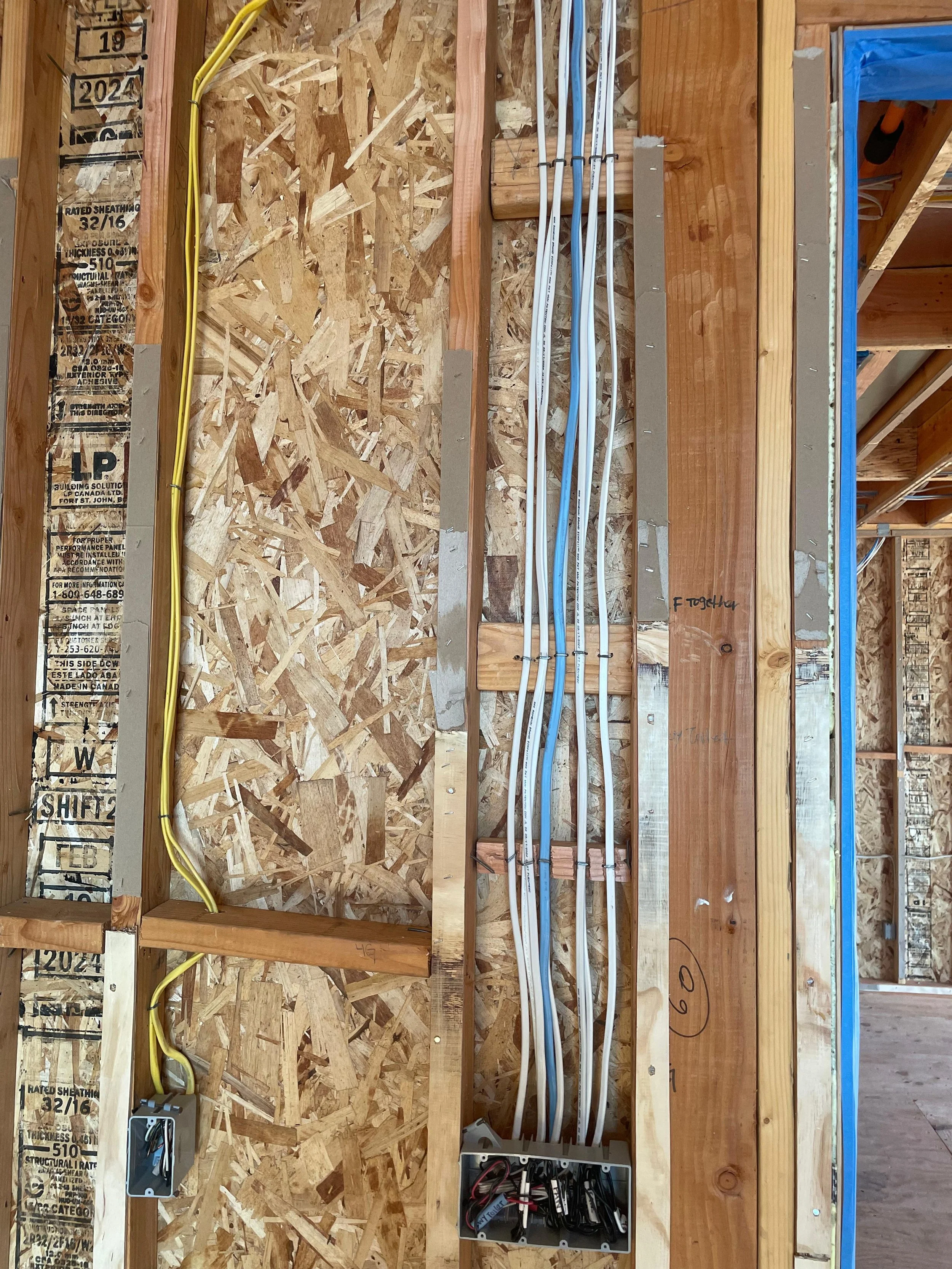 Construction wall with electrical wiring, conduit pipes, and junction boxes installed.