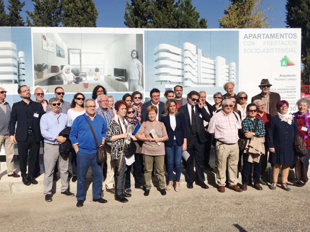 Socios de Vitápolis frente al cartel de obras en la parcela donde se están construyendo las viviendas.