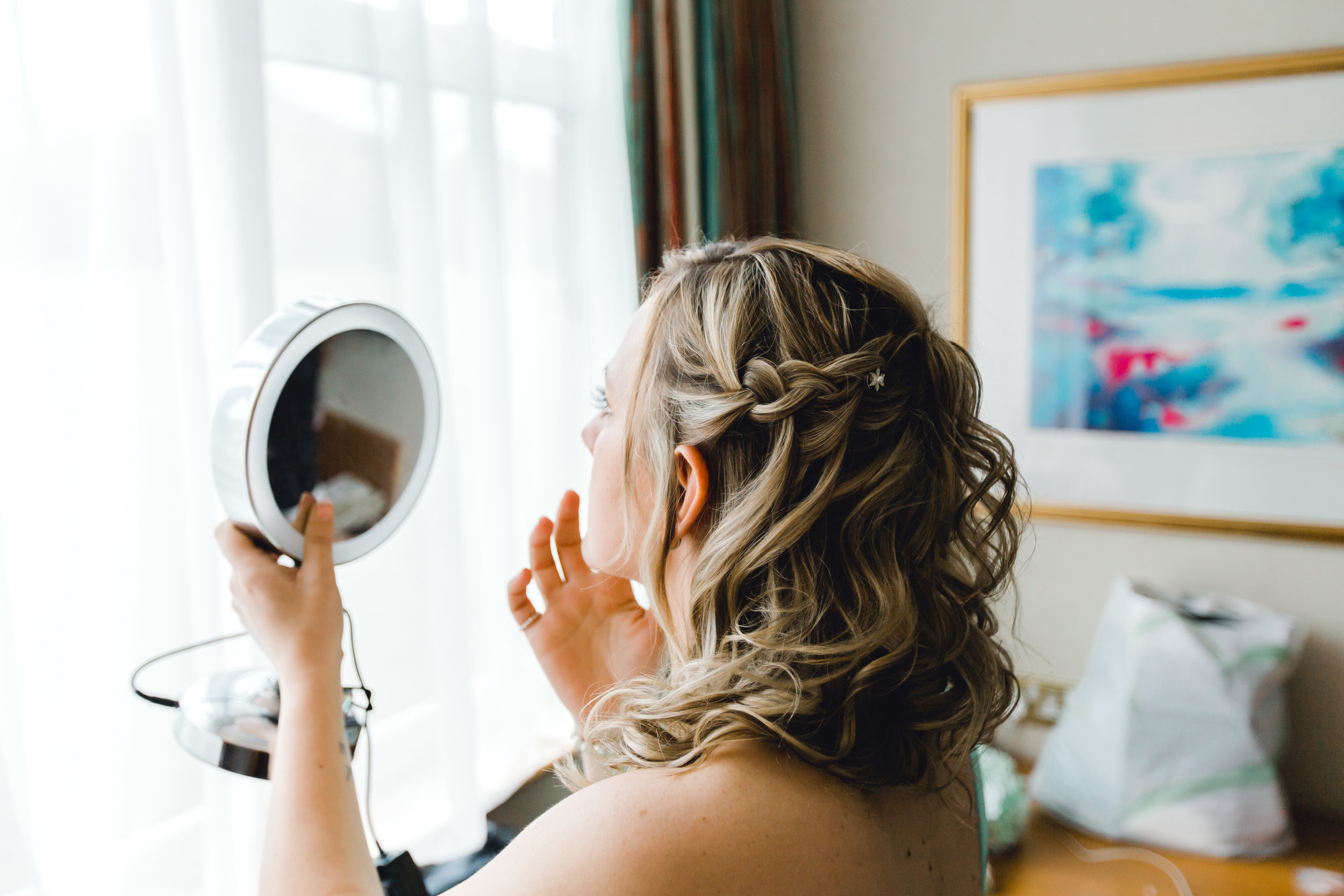 Bridesmaid using mirror to prepare and get ready for the big day